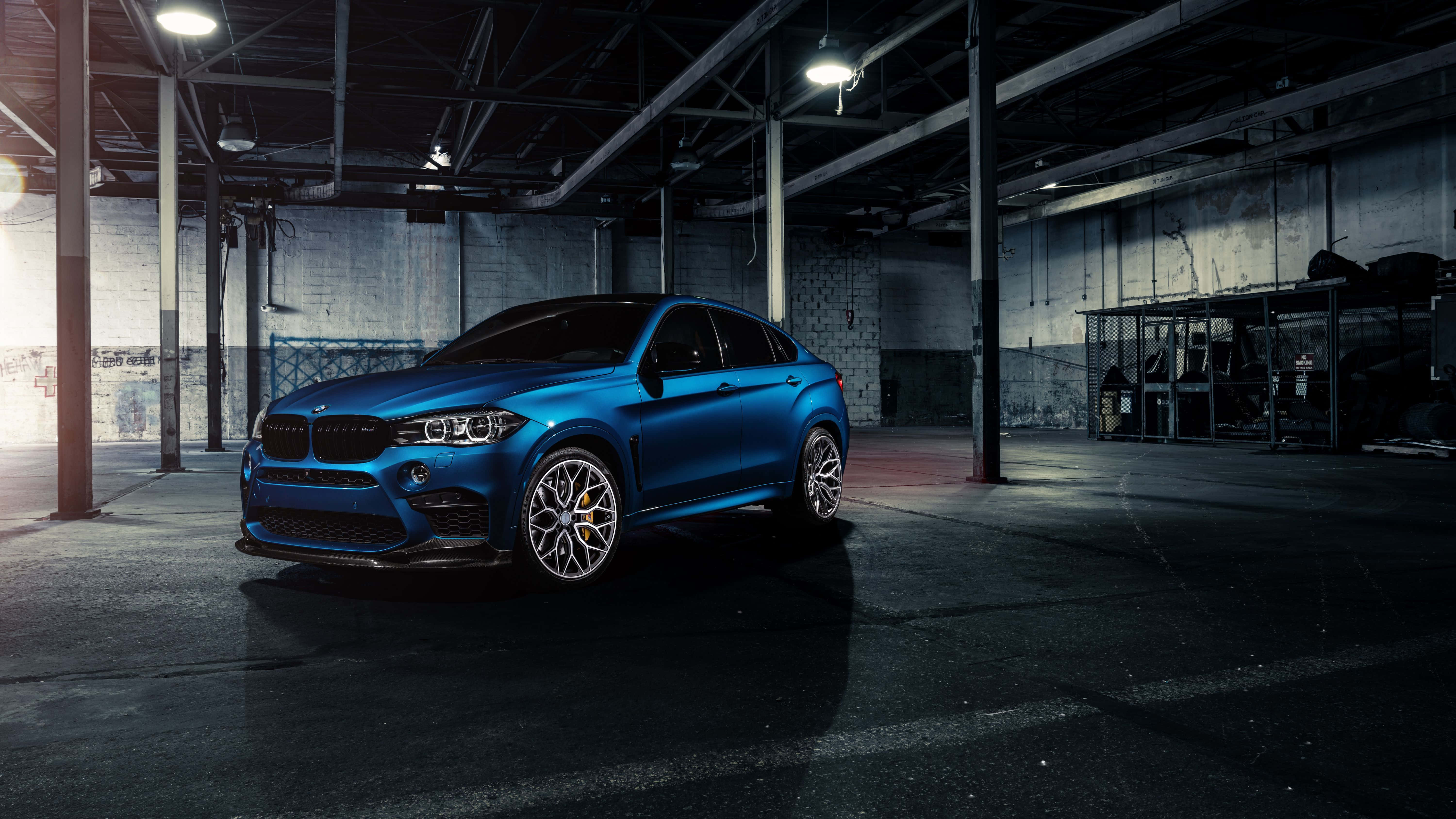 Bmw X6 M 桌布 壁紙 — 一輛光澤藍色BMW X6 M Coupe在工業燈光下閃耀，身處一個有裸露橫樑和混凝土牆的粗糙倉庫中。