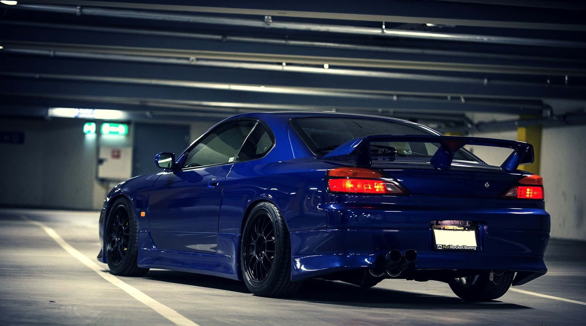 跑車 桌布 壁紙 — 一輛光澤藍色的日產Skyline GT-R停放在燈光昏暗的地下停車場，紅色尾燈閃爍。