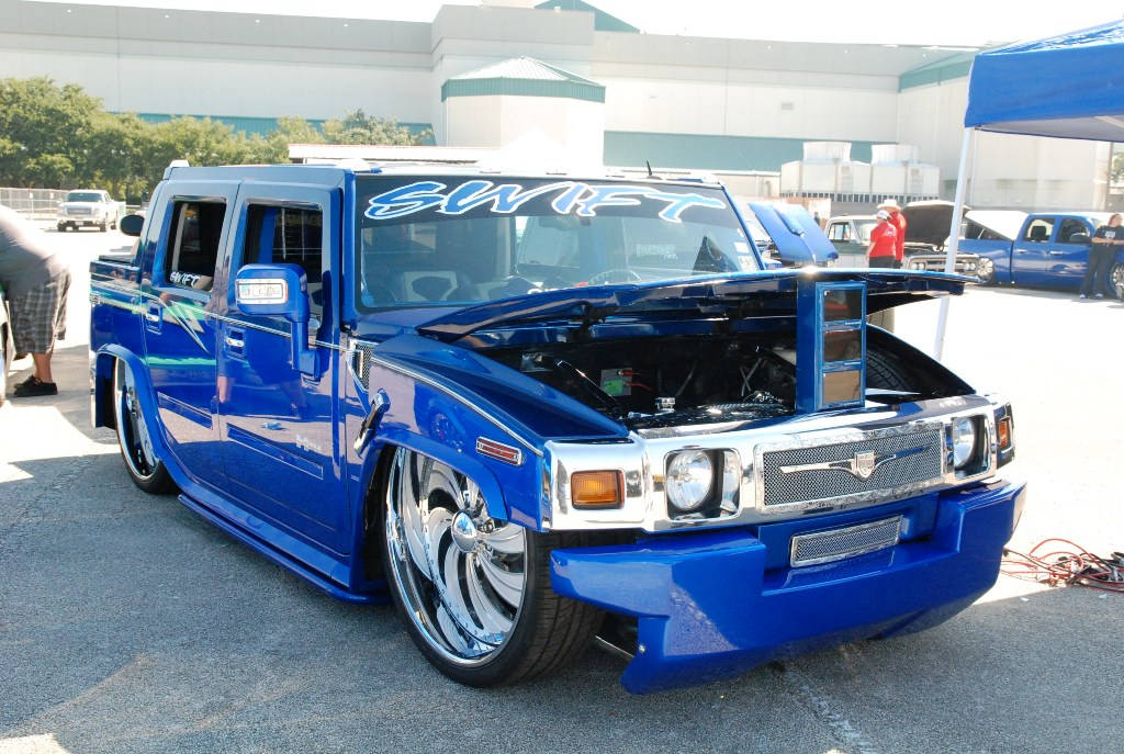 Trucks 桌布 壁紙 — 一輛光澤藍色訂製Hummer H2，引擎蓋打開，在明亮的日光下於車展中展示引擎改裝。
