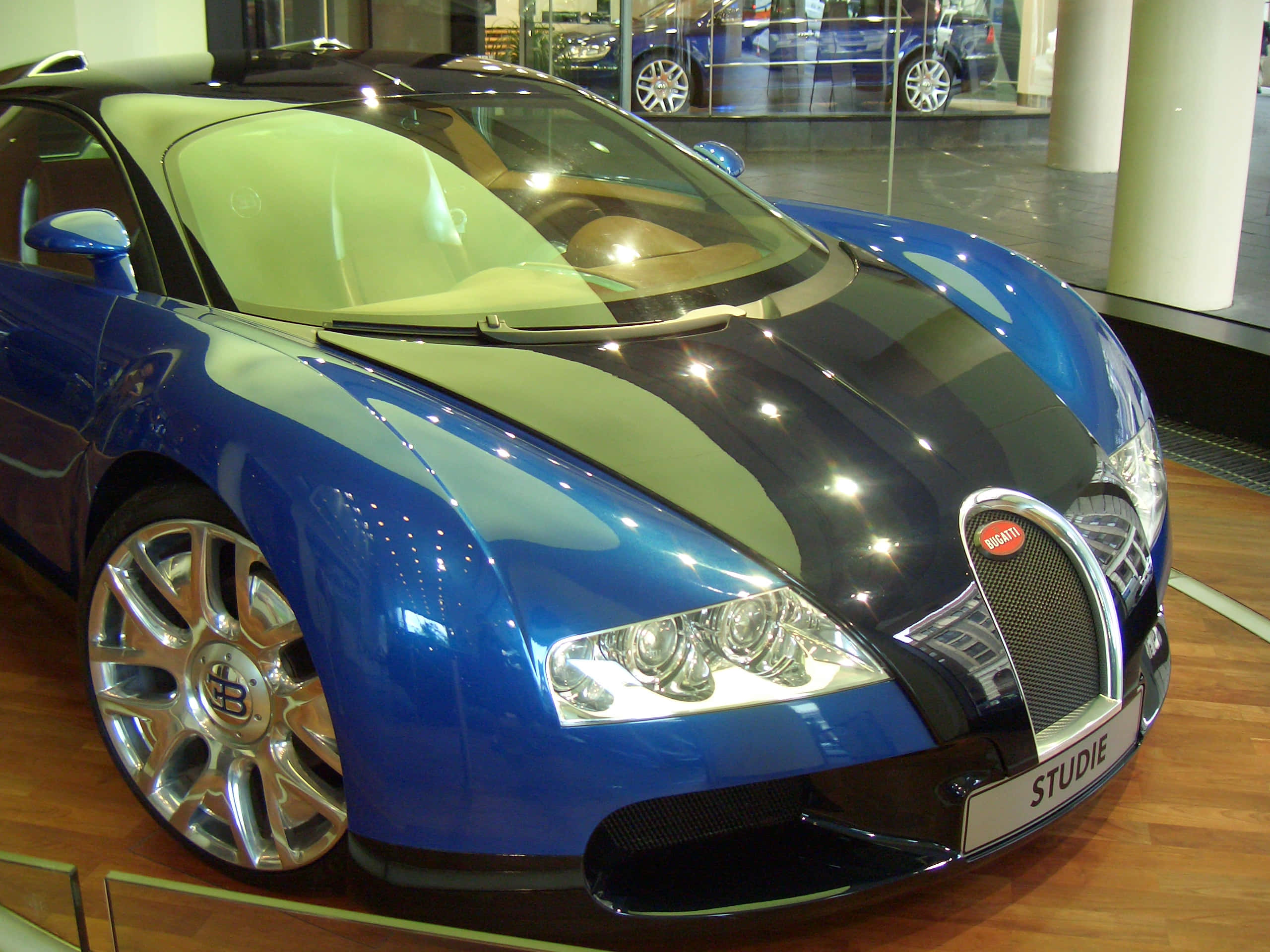 桌布 壁紙 — 一輛光澤藍黑Bugatti跑車配銀色輪圈，在室內木地板上展示。