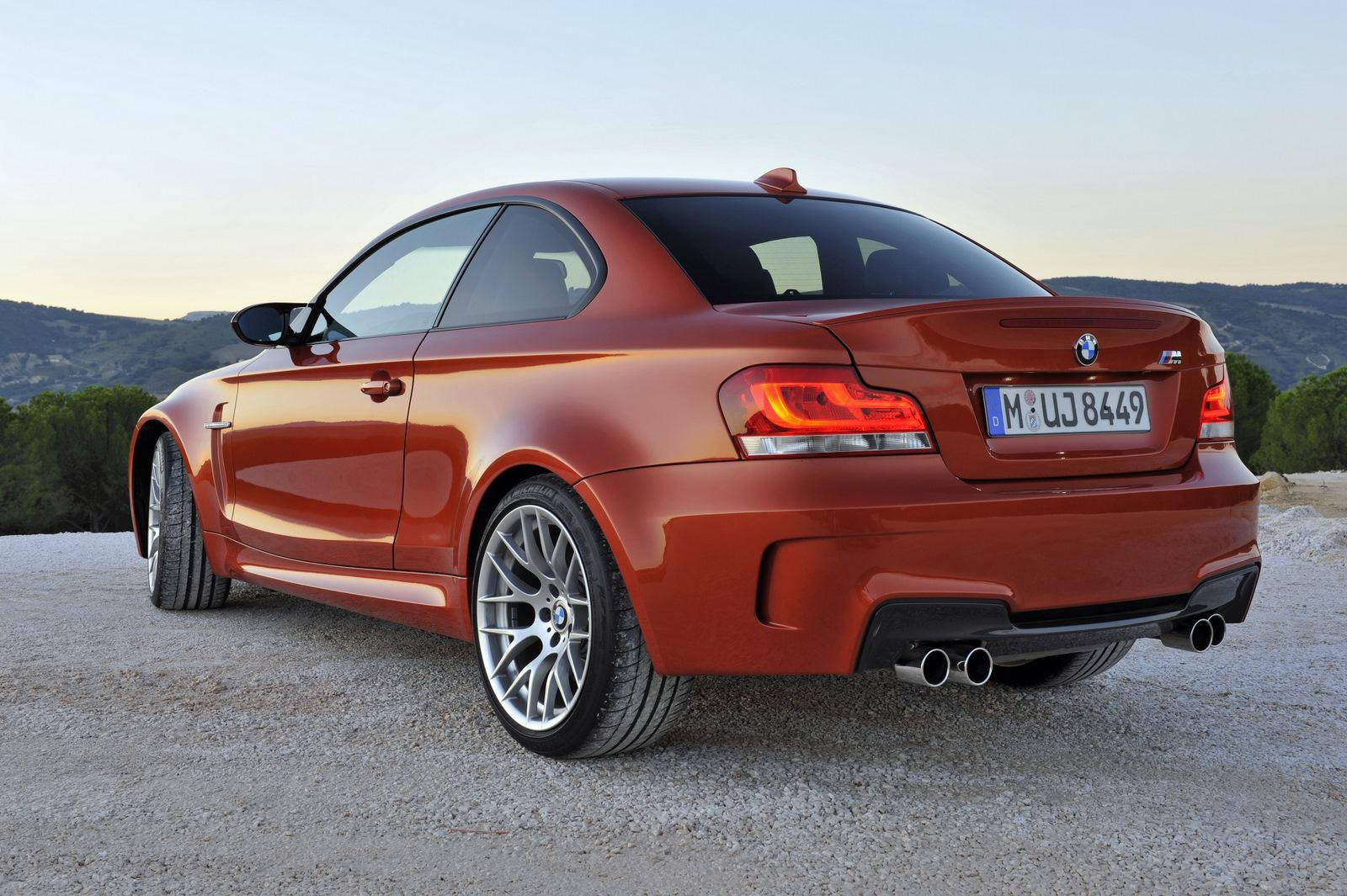 m 桌布 壁紙 — 一輛光澤銅色BMW M3雙門跑車停在碎石路上，背景是柔和夕陽下的山丘和樹木。