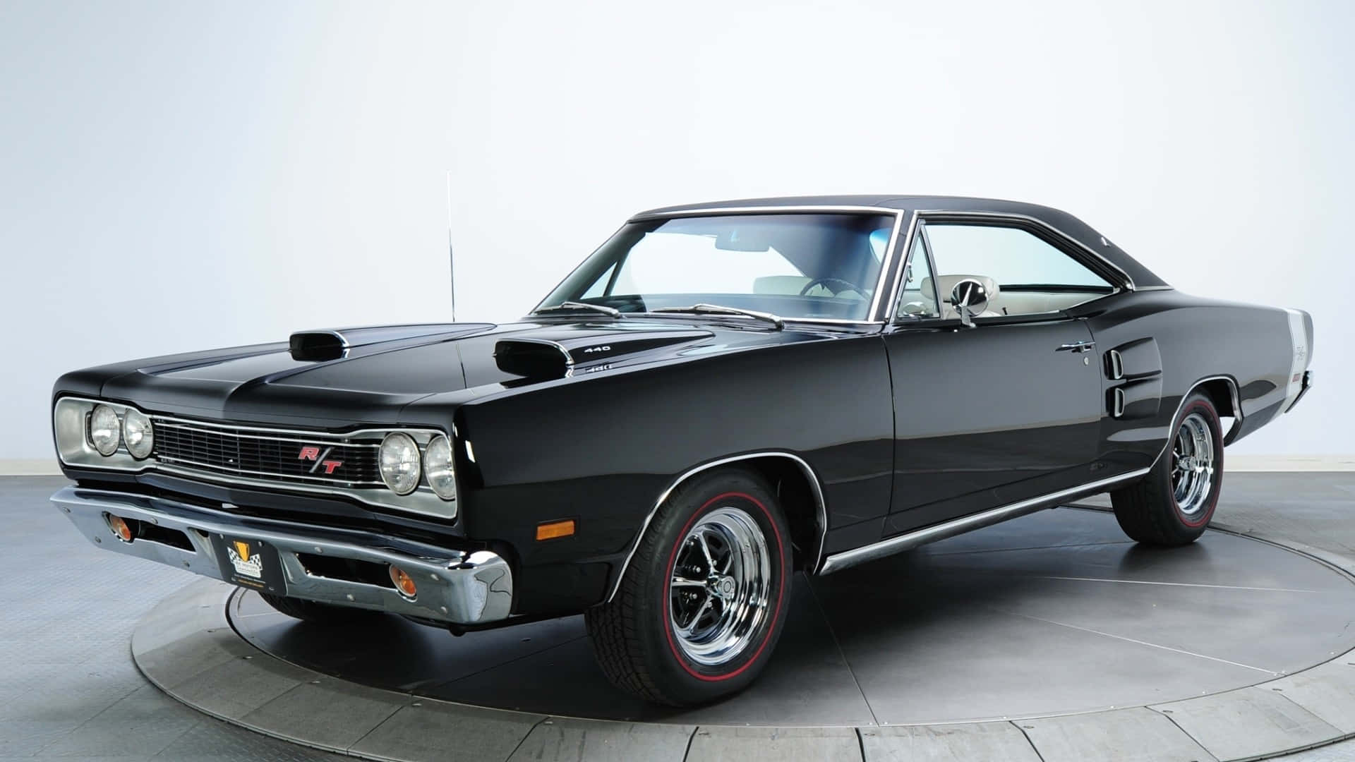 Black Car 桌布 壁紙 — 一輛光澤黑色1960年代道奇Charger RT肌肉車，配備紅線輪胎和鍍鉻裝飾，放置在工作室轉盤上。