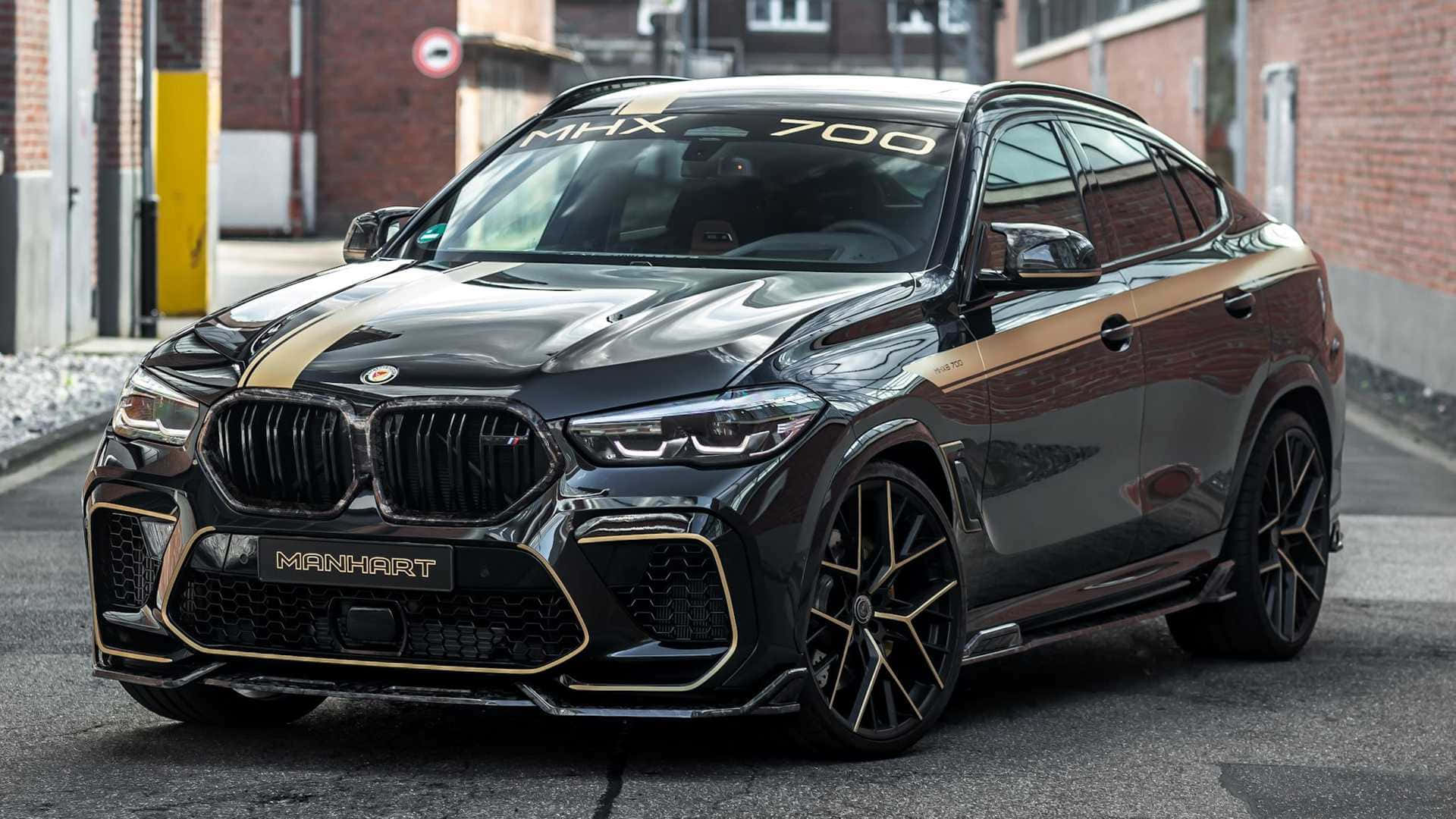 BMW X6 M 桌布 壁紙 — 一輛光澤黑色Manhart改裝BMW X6 M，帶金色點綴，停在磚砌城市街道上。