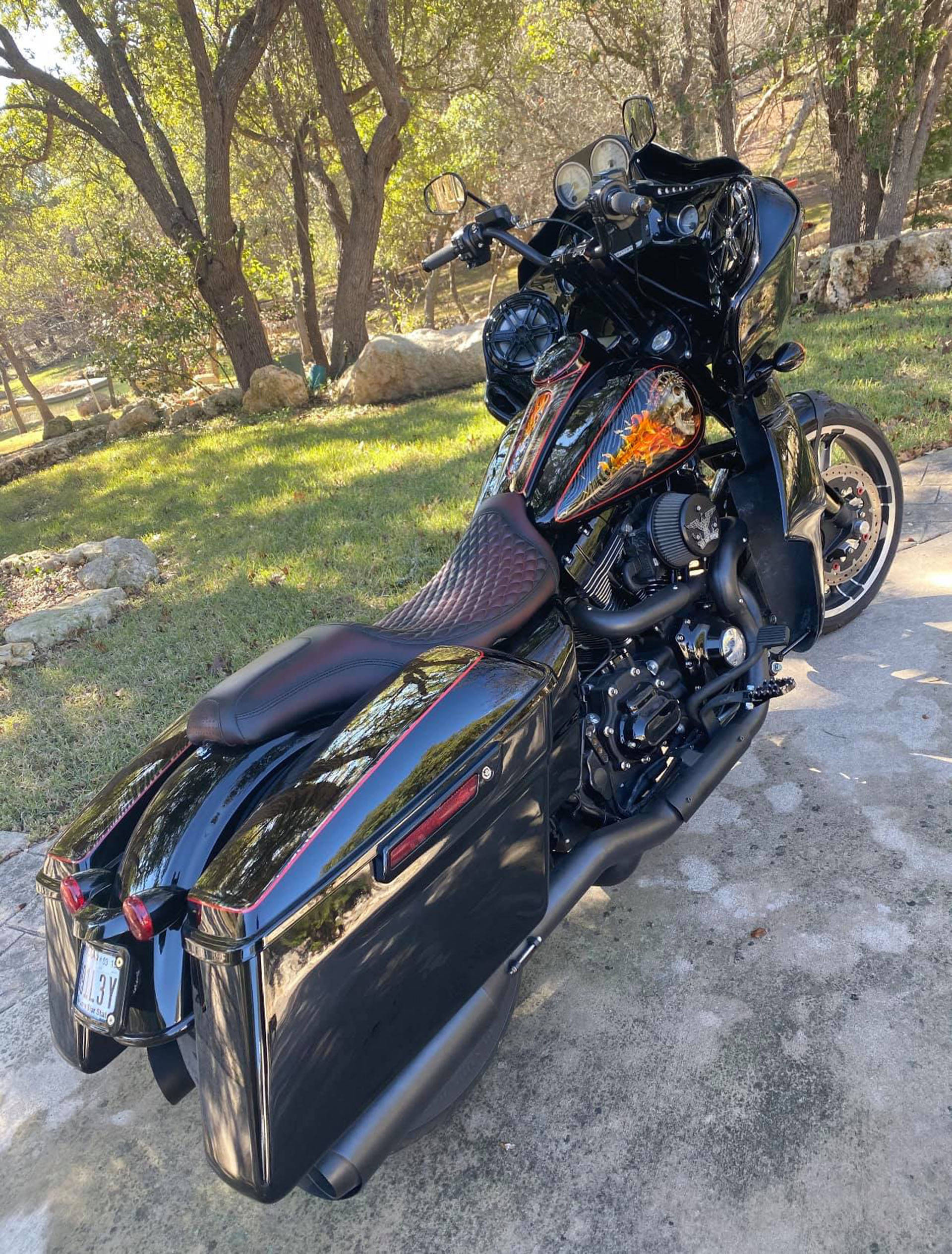 Choppers 桌布 壁紙 — 一輛光澤黑色旅行機車帶有自訂火焰貼紙，停放在混凝土墊上，周圍是陽光照射的樹木和草地。