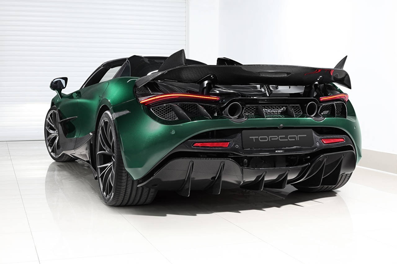跑車 桌布 壁紙 — 一輛光面綠色McLaren超級跑車，配備大型碳纖維尾翼和紅色尾燈，停放在室內白色地板上。