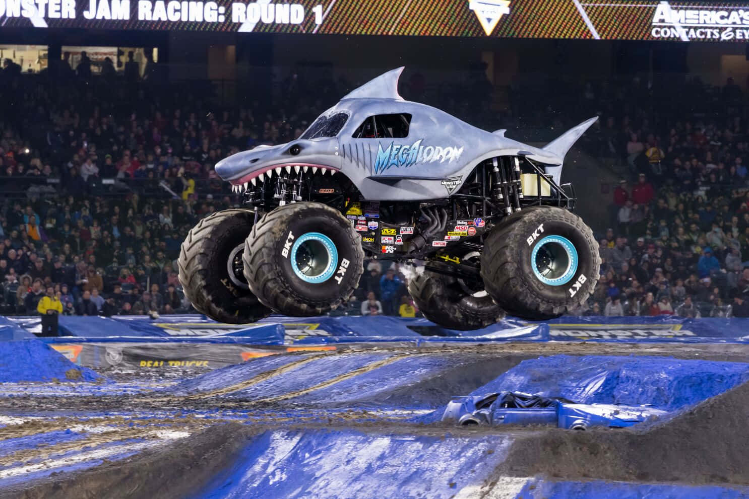 鯊魚 桌布 壁紙 — 一輛名為 Megalodon 的鯊魚主題怪獸卡車在 Monster Jam 活動期間，在擠滿人的室內競技場中飛越藍色坡道。