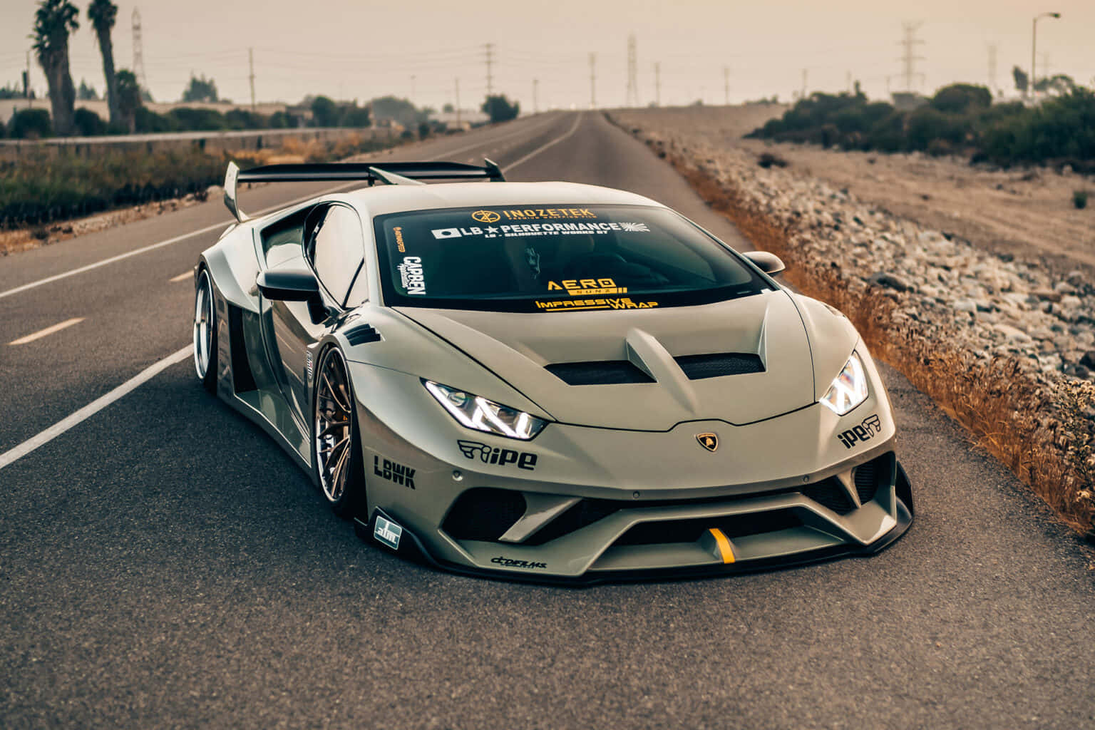 Lamborghini Silhouette 桌布 壁紙 — 一輛啞光灰色藍寶堅尼Huracán賽車，配備定制空氣動力學套件，在朦朧日光下於沙漠高速公路奔馳。