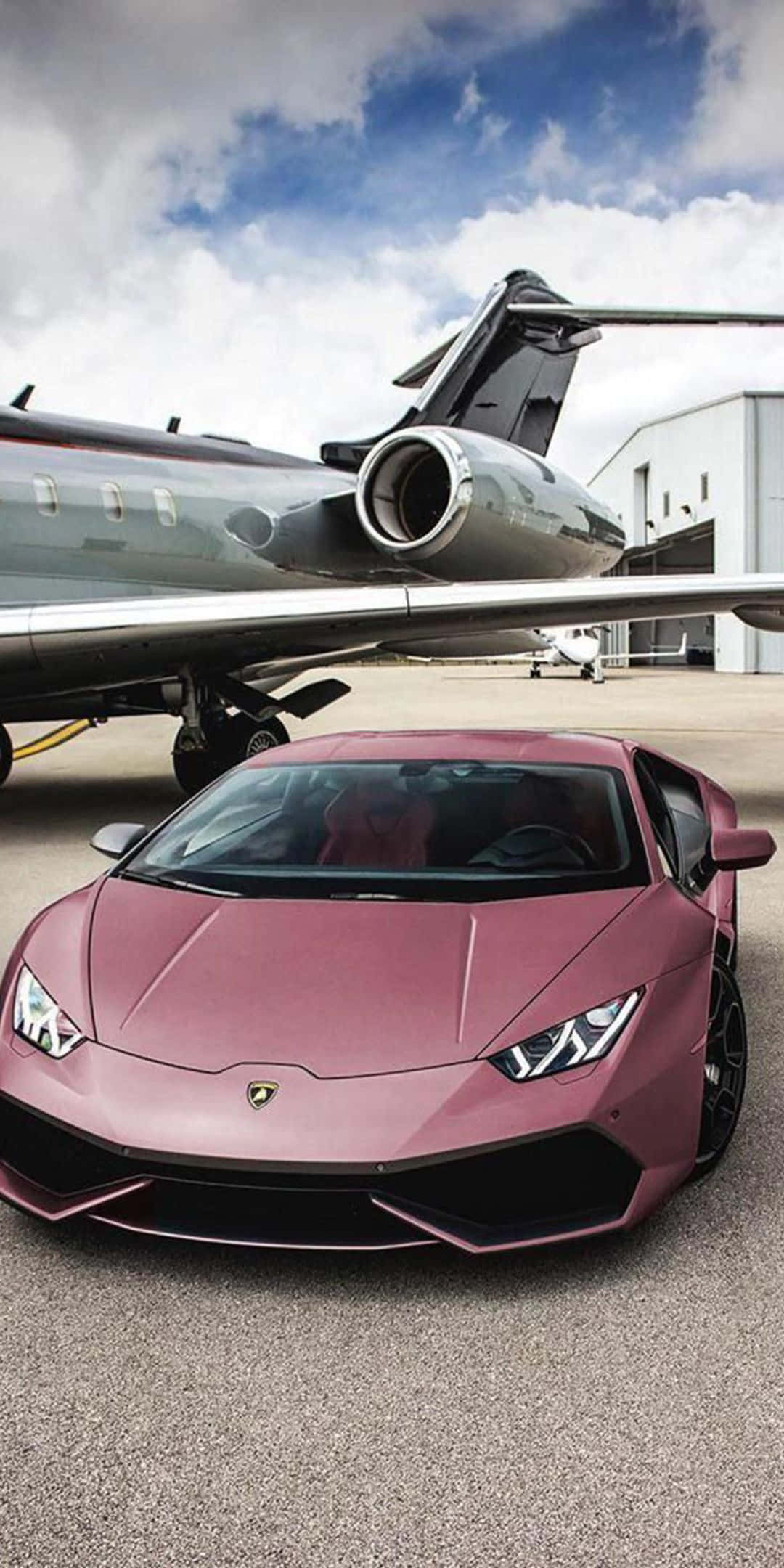 Pixel 3 Lamborghini 桌布 壁紙 — 一輛啞光粉紅色藍寶堅尼 Aventador 停放在機場機庫的私人飛機下方的柏油路面上。