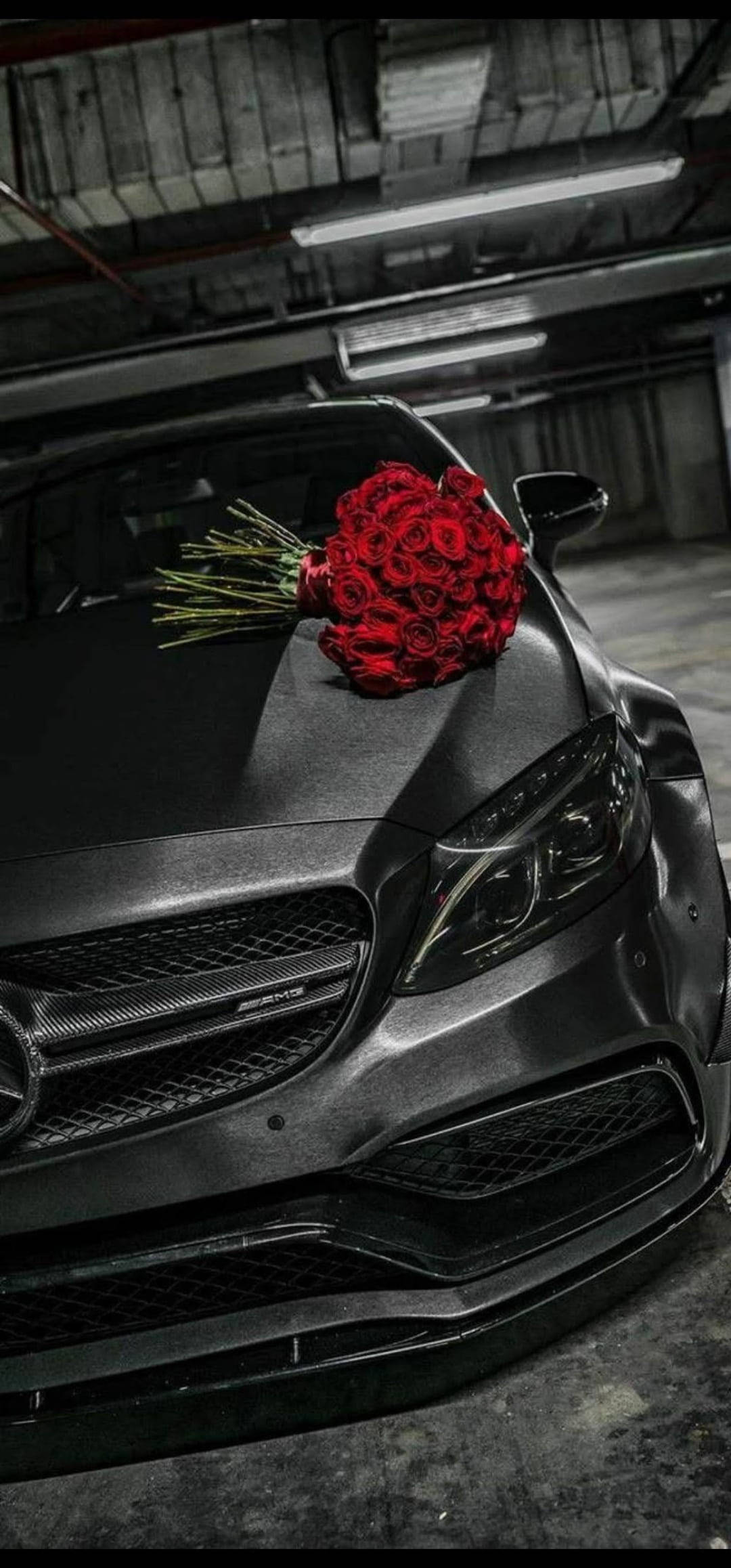 X 桌布 壁紙 — 一輛啞光黑色的 Mercedes-AMG 跑車停在昏暗的車庫中，引擎蓋上放著一束鮮豔的紅玫瑰。