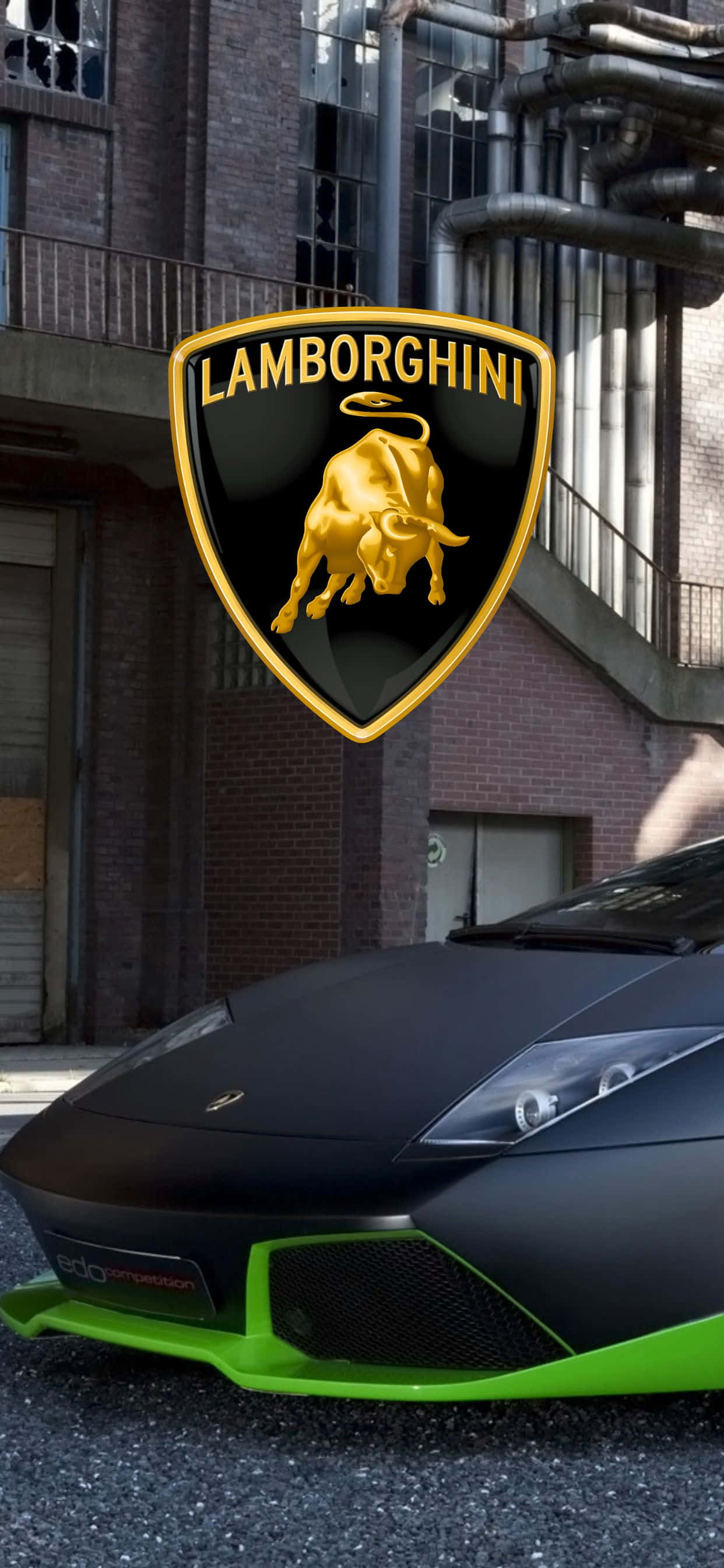 Lamborghini Phone 桌布 壁紙 — 一輛啞光黑色藍寶堅尼帶有螢光綠色點綴，停在一棟帶有大型金色公牛標誌的磚砌建築前。