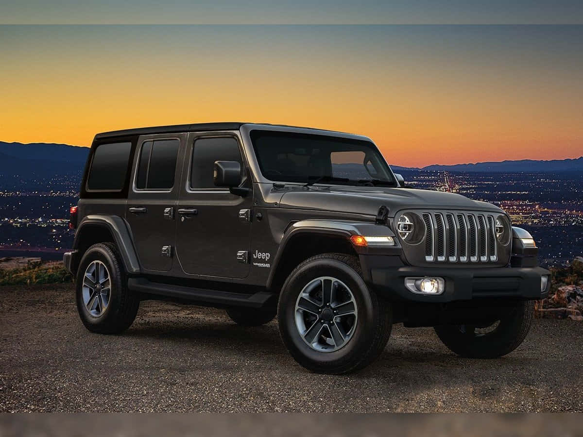 吉普 桌布 壁紙 — 一輛啞黑色Jeep Wrangler站在山頂上，在日落時分俯瞰著發光的城市景觀和遠處的山脈。