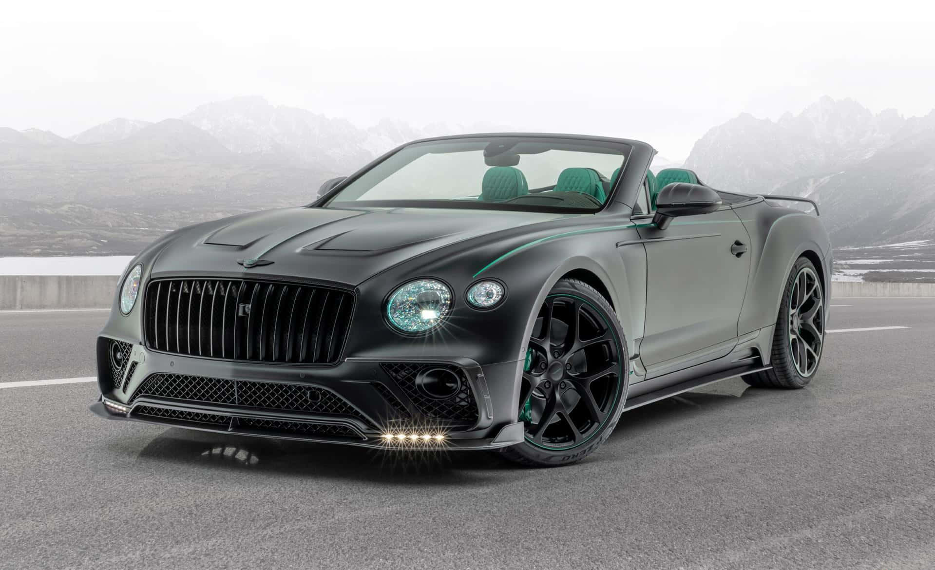 Bentley Continental Gt Convertible 桌布 壁紙 — 一輛啞黑色賓利敞篷車，綠色內裝，停在路上，背景是積雪的山脈。