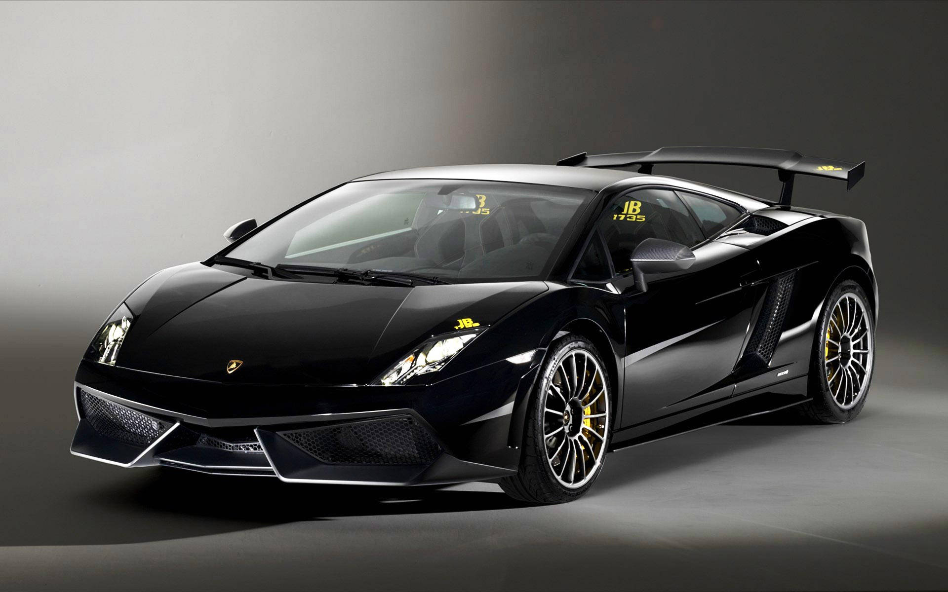Lamborghini 4K 桌布 壁紙 — 一輛在攝影棚內擺拍的黑色藍寶堅尼Gallardo，帶有黃色點綴和後尾翼。