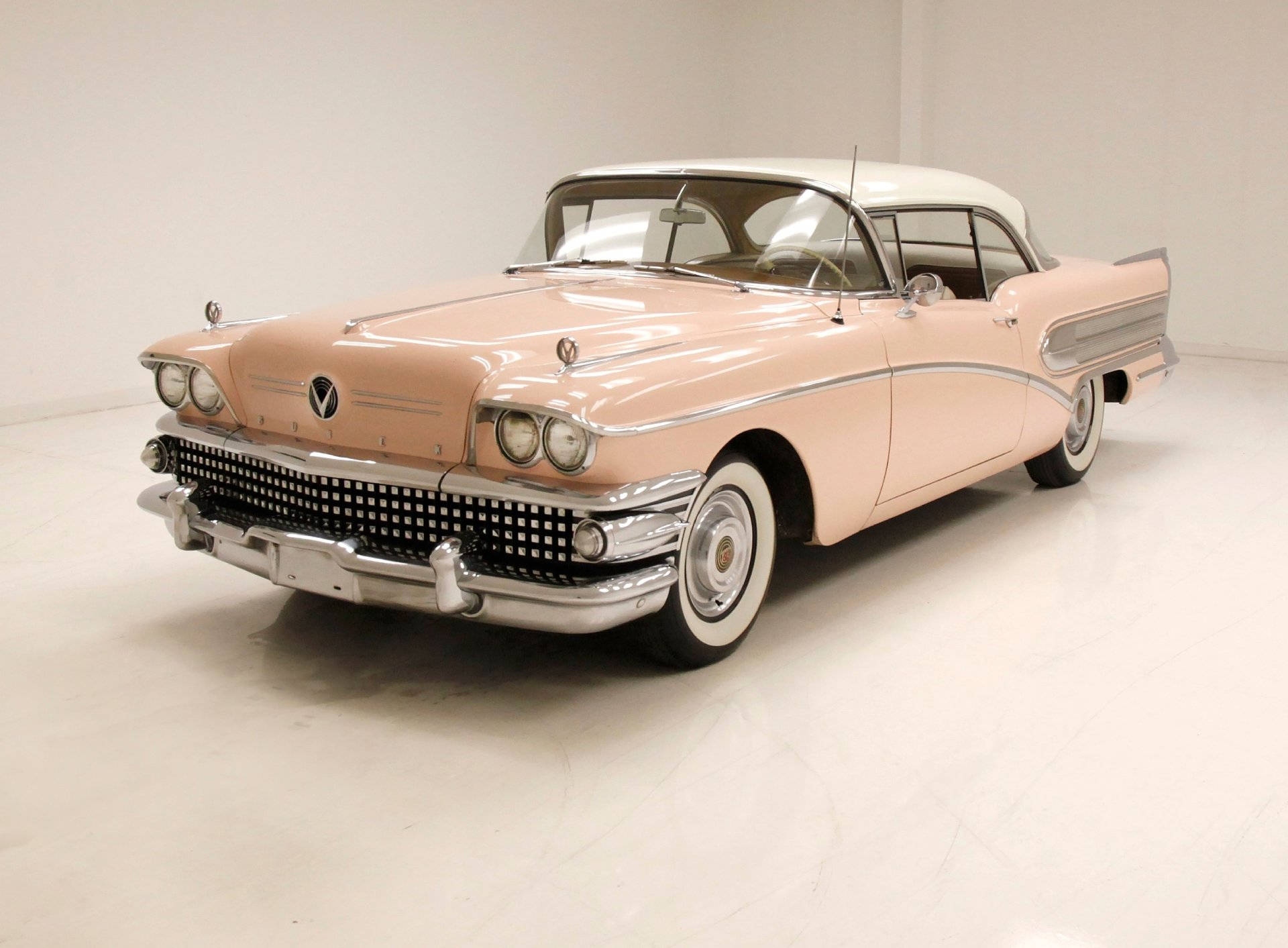 Buick 桌布 壁紙 — 一輛在明亮工作室中展示的粉白相間1950年別克Roadmaster經典車，帶有鍍鉻飾條和白邊輪胎。