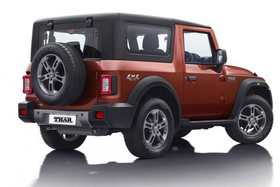 吉普 桌布 壁紙 — 一輛堅固的橙色Mahindra Thar SUV，帶有黑色飾邊和安裝在後門上的備用輪胎，站在反射性白色工作室地板上。