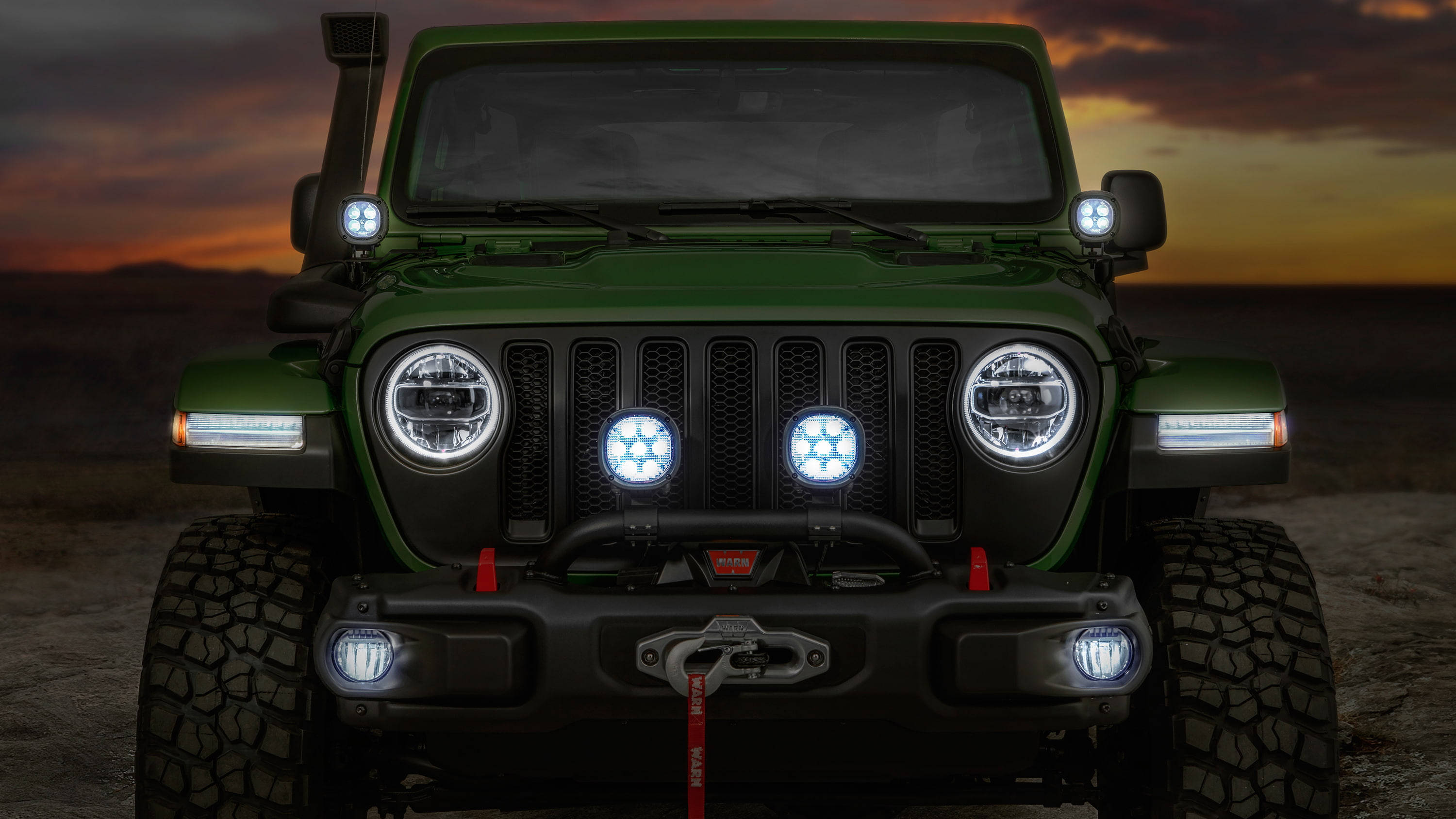 美學 桌布 壁紙 — 一輛堅固的綠色Jeep Wrangler配備明亮的LED燈，在日落時分的沙漠景觀中佔據主導地位。