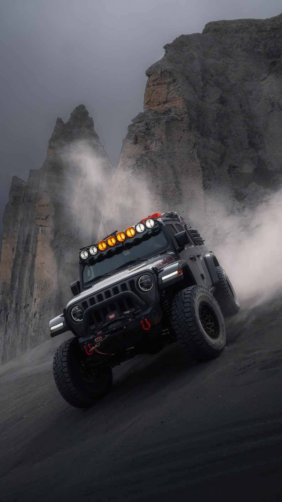 Wrangler 桌布 壁紙 — 一輛堅固的黑色越野Jeep在陰天之下，疾馳穿過戲劇性的岩石峽谷，揚起灰塵。