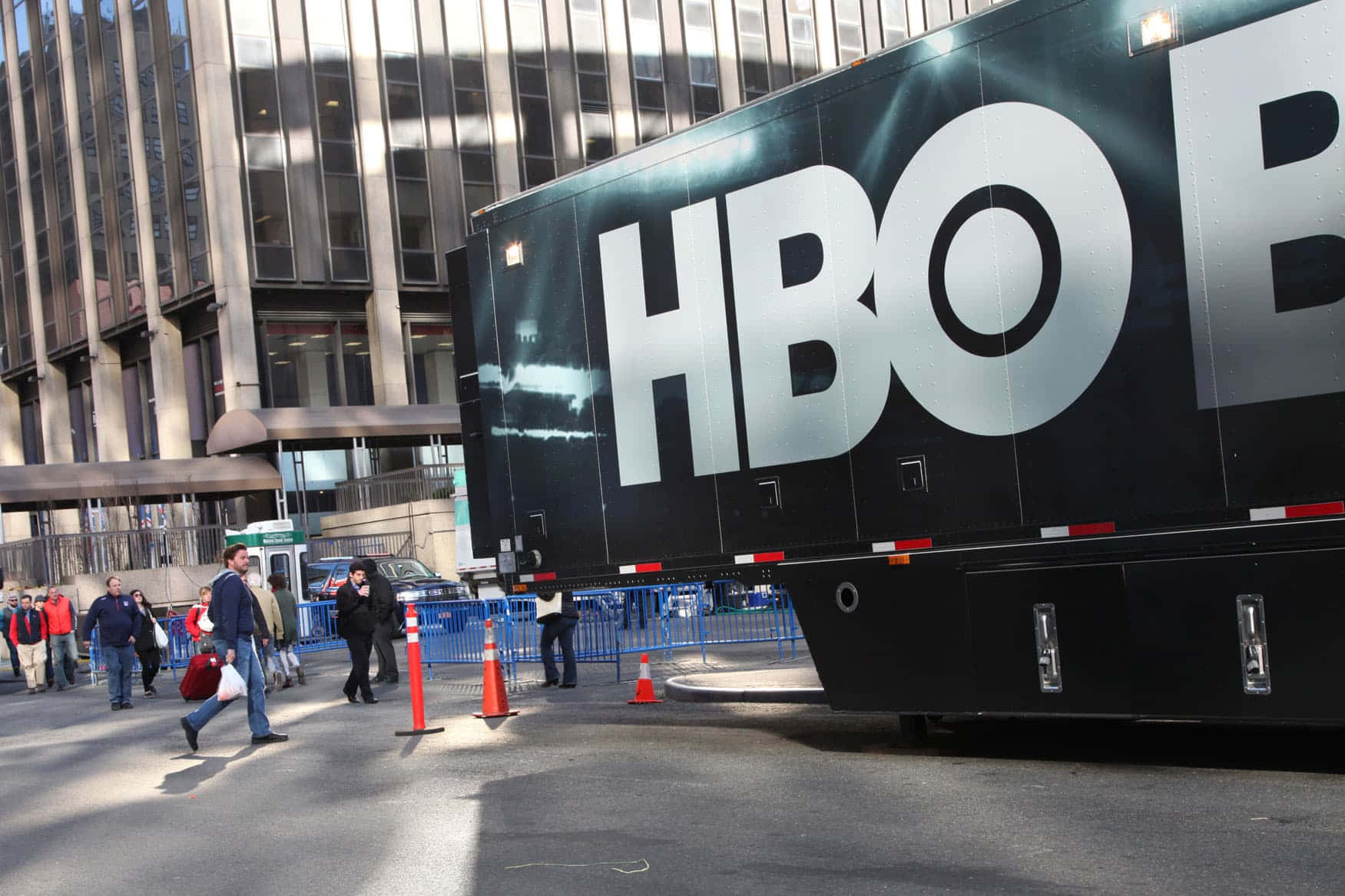 HBO 桌布 壁紙 — 一輛大型黑色HBO宣傳貨車停放在城市街道上，附近有行人走過。