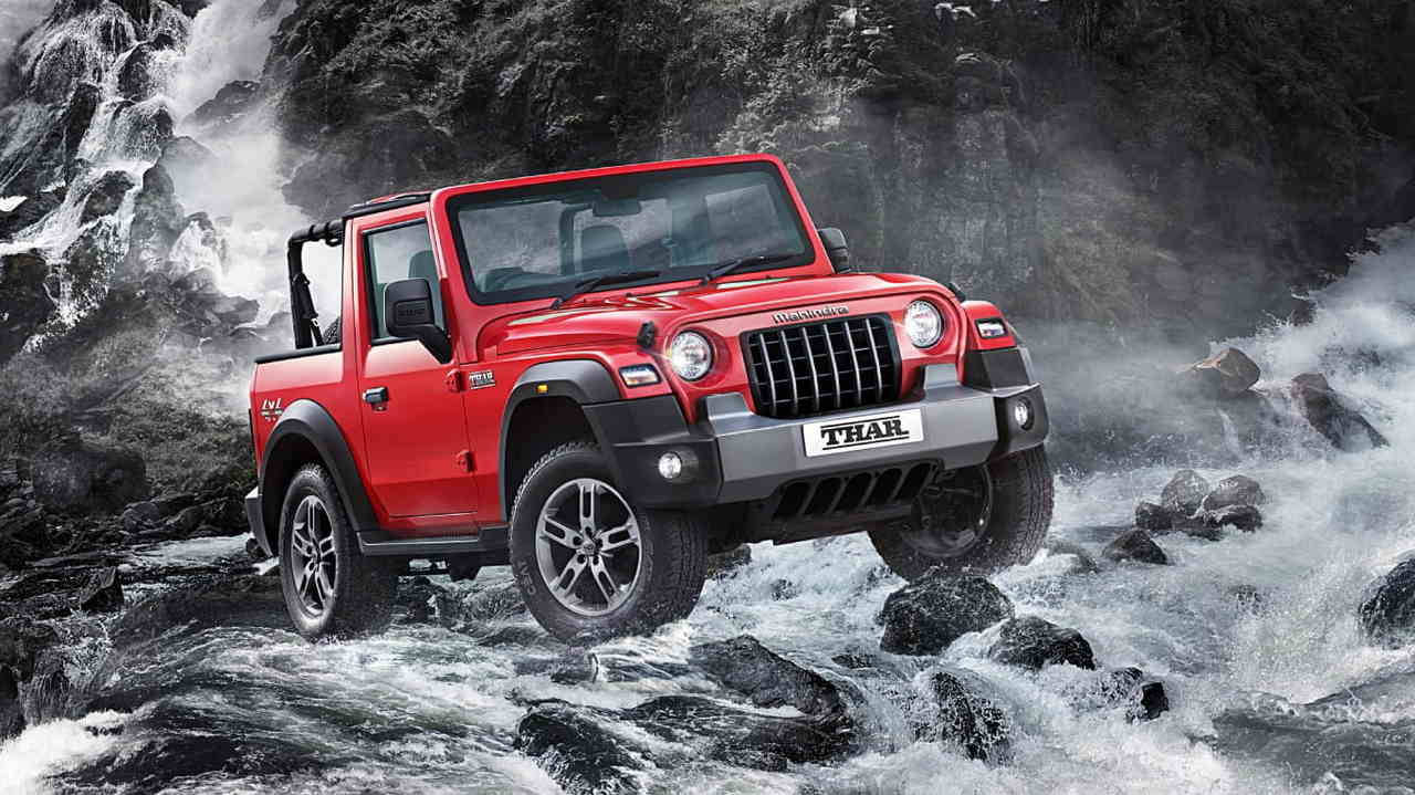 吉普 桌布 壁紙 — 一輛大膽的紅色 Mahindra Thar SUV 征服了咆哮的岩石河流，伴隨著霧氣和飛濺的水花。