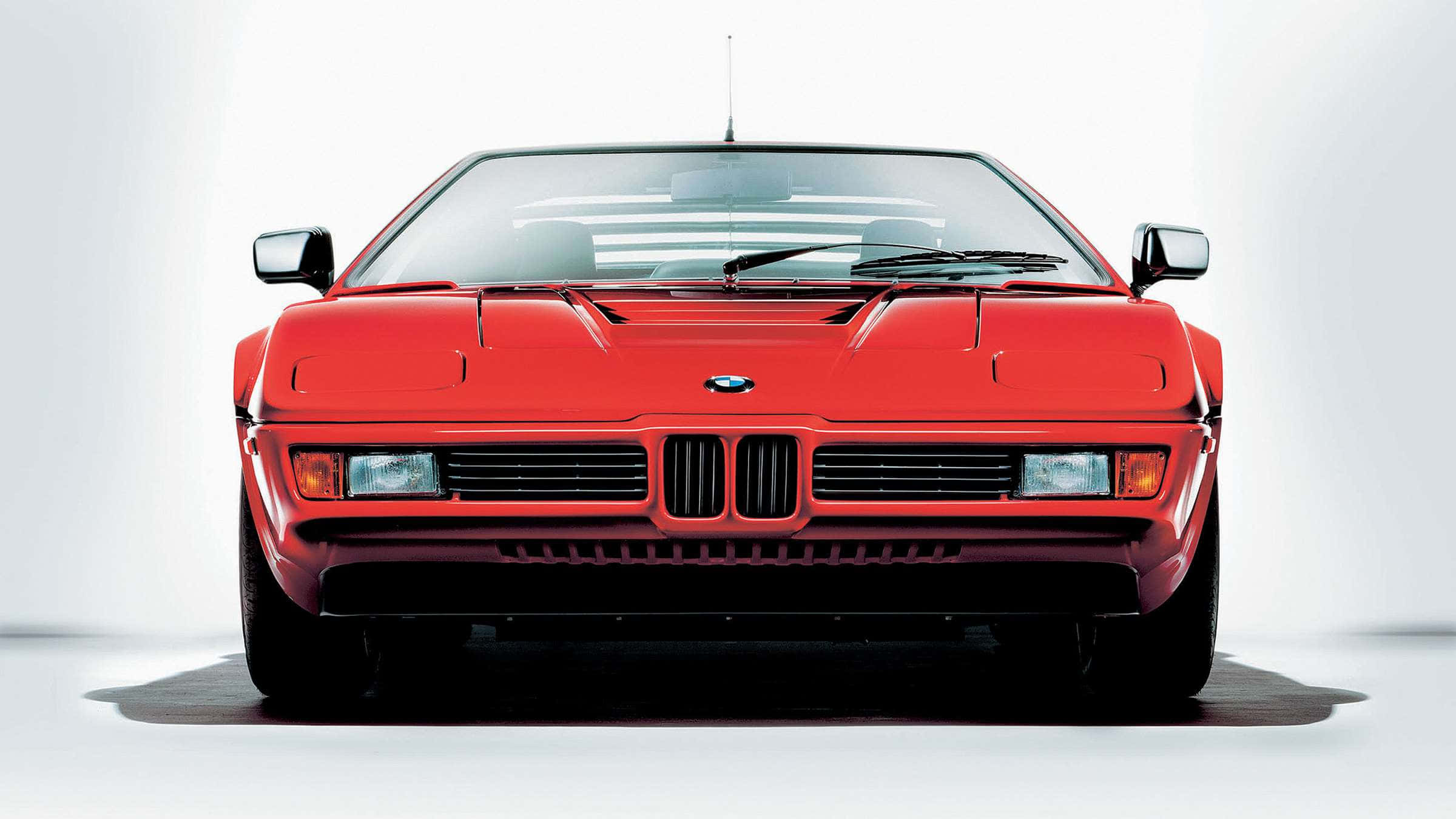 Best M Series 桌布 壁紙 — 一輛大膽的紅色BMW M1跑車在純白工作室背景前正面朝前，帶有戲劇性的陰影。