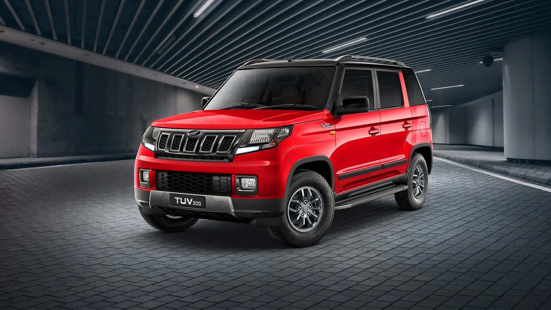 Mahindra 桌布 壁紙 — 一輛大膽的紅色SUV，帶有黑色飾邊和銀色點綴，醒目地停在一個時尚現代的地下停車場，灰色瓷磚地板和工業照明。