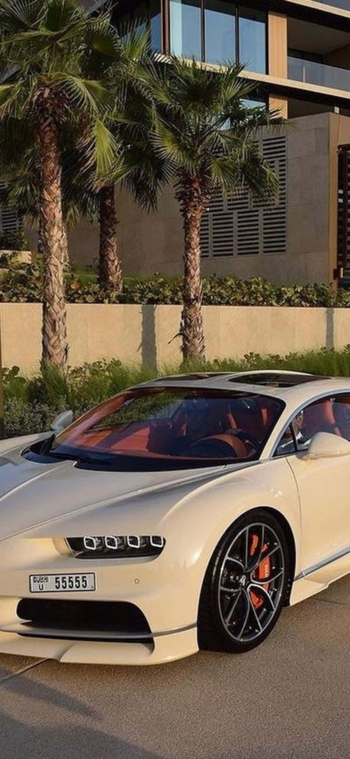 iPhone Xs Bugatti 桌布 壁紙 — 一輛奶油色布加迪Chiron停在一棟現代別墅前，別墅旁有棕櫚樹，沐浴在金色夕陽下。