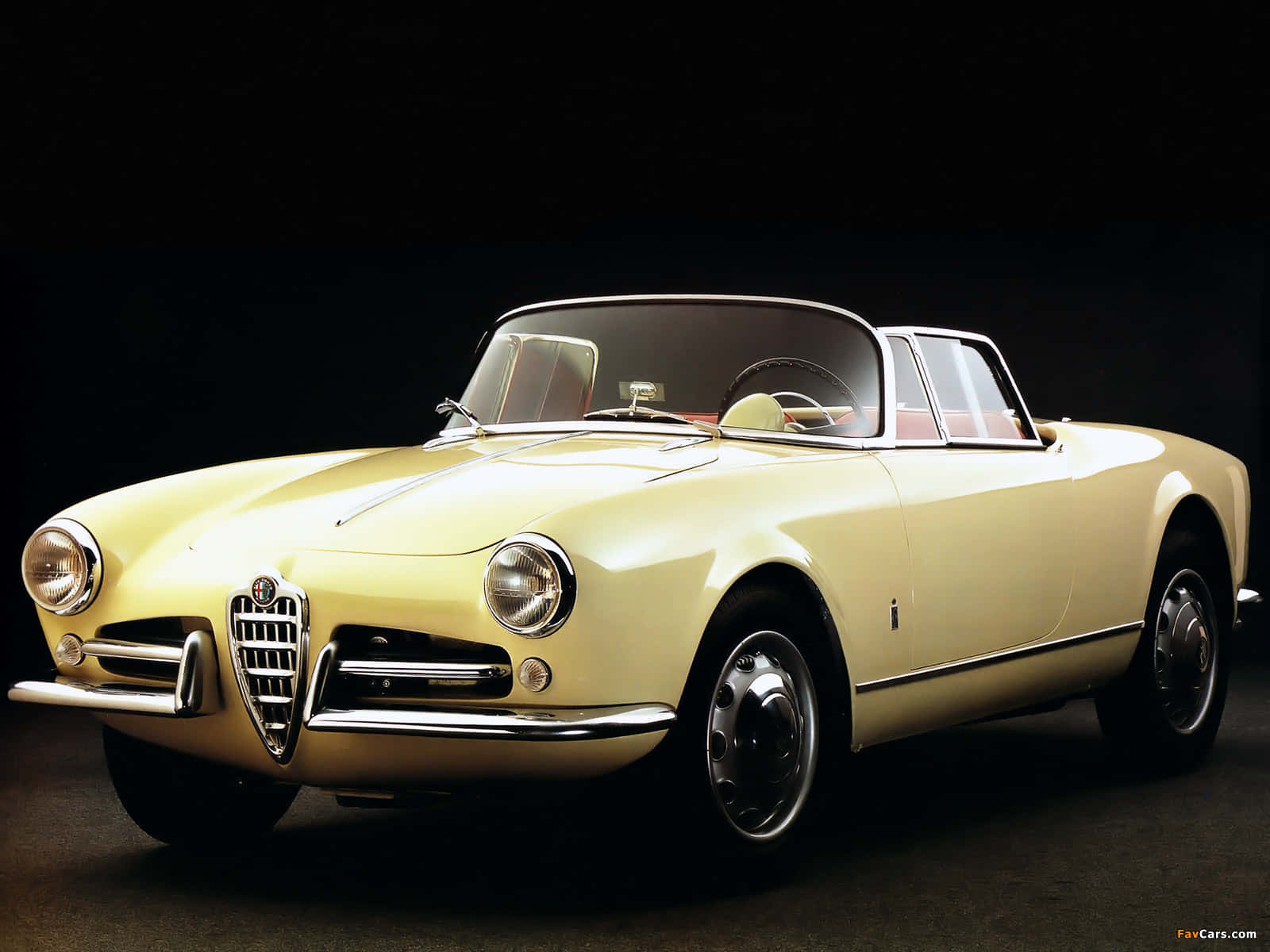 Alfa Romeo Spider 桌布 壁紙 — 一輛奶油黃色的經典愛快羅密歐Spider敞篷車在攝影棚燈光下，在純黑背景中閃閃發光。