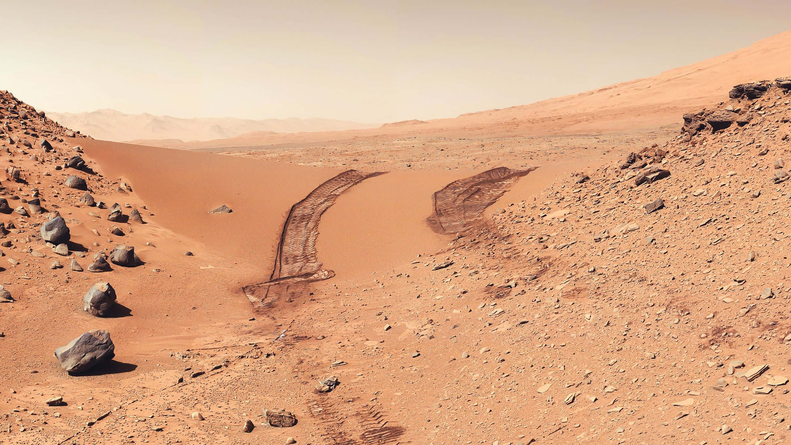 Mars Landscape 桌布 壁紙 — 一輛孤獨的探測車在朦朧的橙色天空下，穿越廣闊的紅色火星沙漠，留下輪胎痕跡。