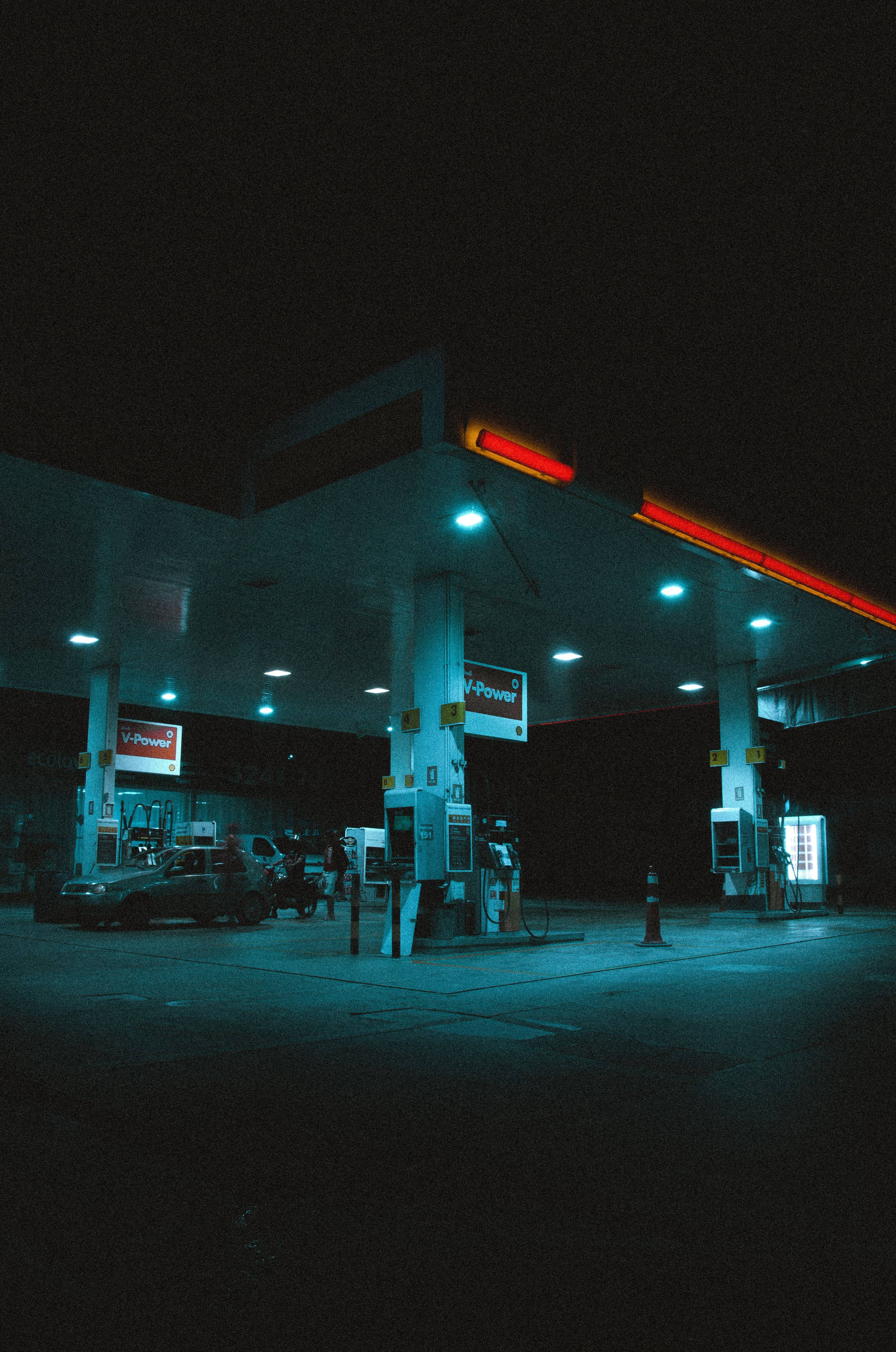 Gas Station 桌布 壁紙 — 一輛孤獨的汽車在加油站，霓虹燈在黑暗的夜空中發出紅色和藍色的光芒。