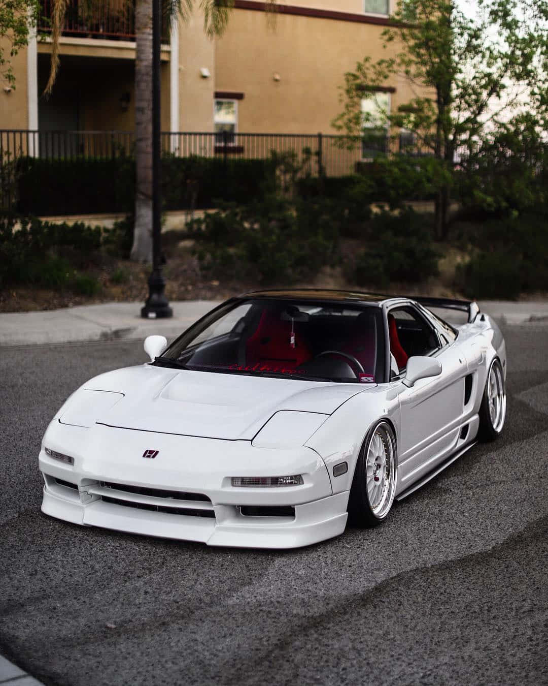 Honda Nsx 桌布 壁紙 — 一輛完美白色本田NSX跑車，紅色內裝，停放在住宅大樓前的柏油路上。