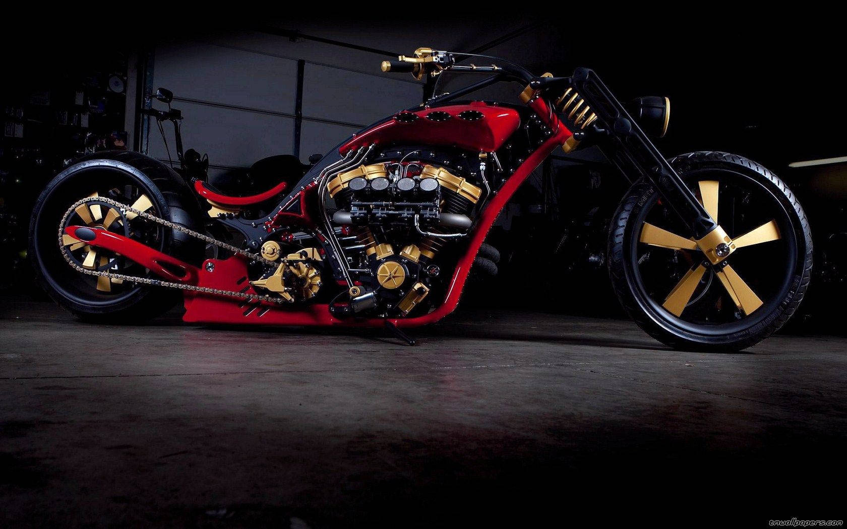 Harley 桌布 壁紙 — 一輛定制的紅金色chopper摩托車，帶有外露引擎和輻條輪，在黑暗的車庫中被戲劇性地照亮。