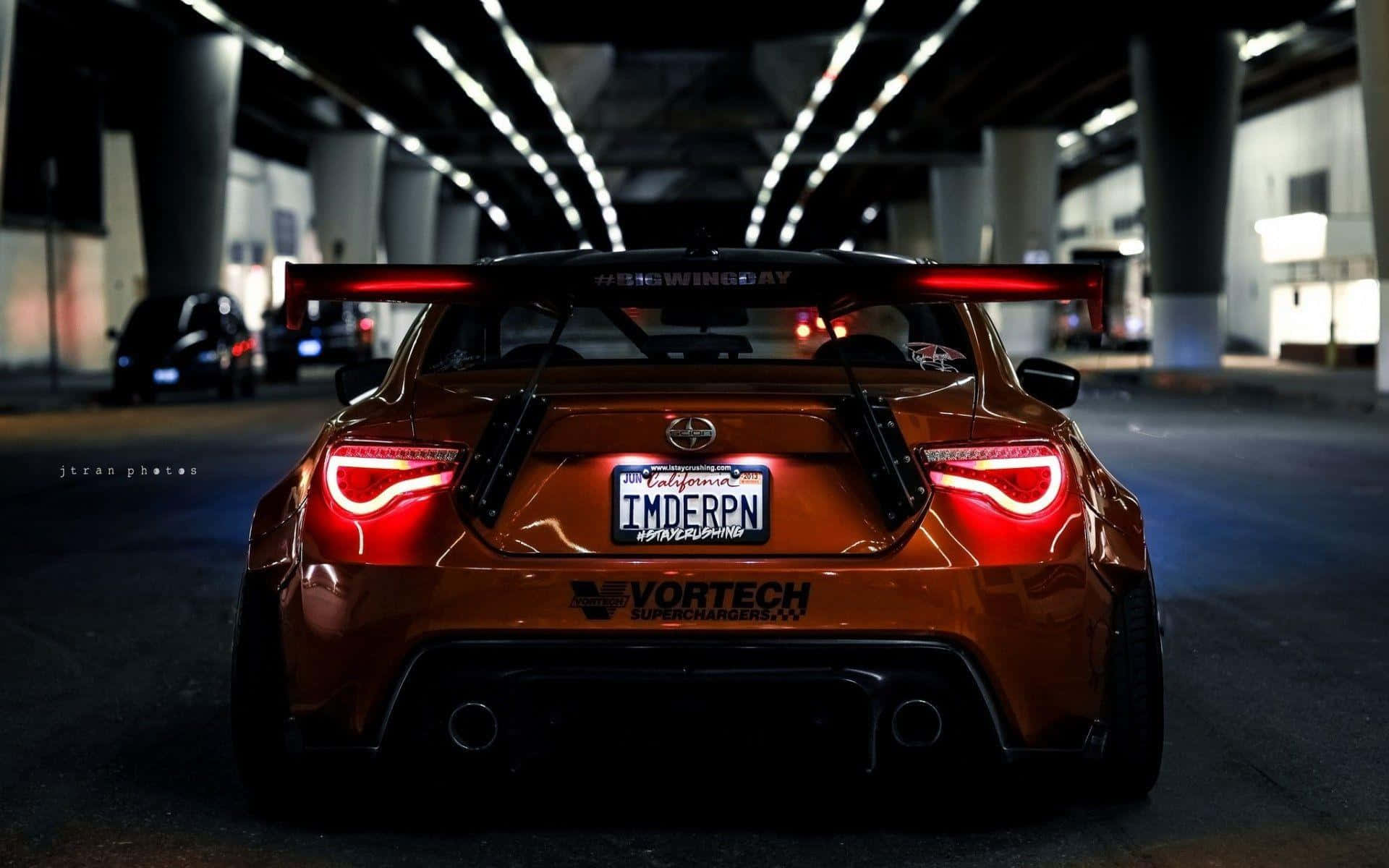 定製的橙色跑車，帶有發光的尾燈，停放在黑暗的城市天橋下。 — Toyota Supra Mk4 壁紙