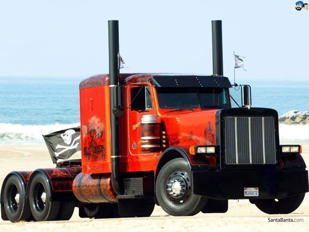 Jacked Up Trucks 桌布 壁紙 — 一輛定製的紅黑色半掛卡車，帶有海盜骷髏圖案，停在沙灘上，旁邊是洶湧的海浪。