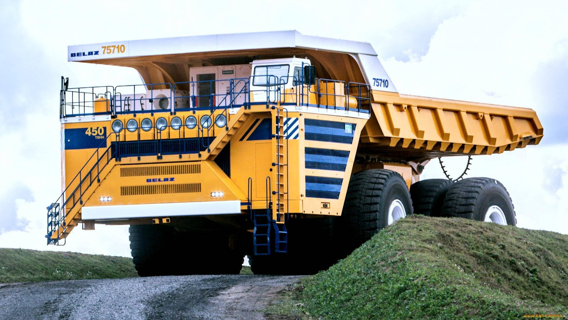 Trucks 桌布 壁紙 — 一輛巨大的黃色BelAZ 75710礦用卡車在陰天下的草坡上佔據主導地位。