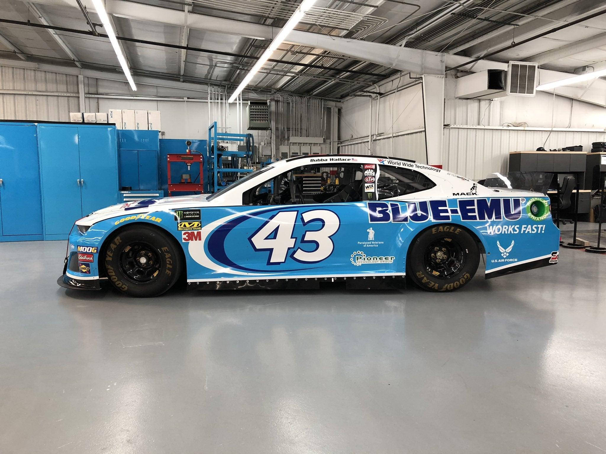 Bubba Wallace 桌布 壁紙 — 一輛帶有「BLUE-EMU」品牌標誌的藍白#43 NASCAR賽車停放在光線充足的車庫內。