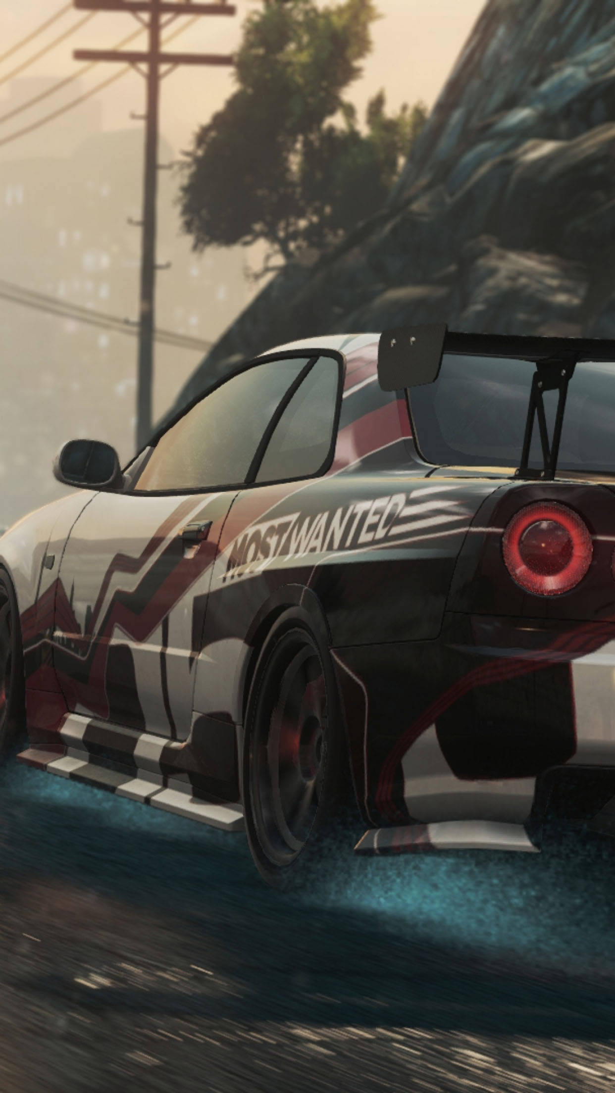 need for speed iPhone 桌布 壁紙 — 一輛帶有 'MOSTWANTED' 貼紙的黑白甩尾車在黃昏時分疾馳穿過煙霧瀰漫的城市峽谷。