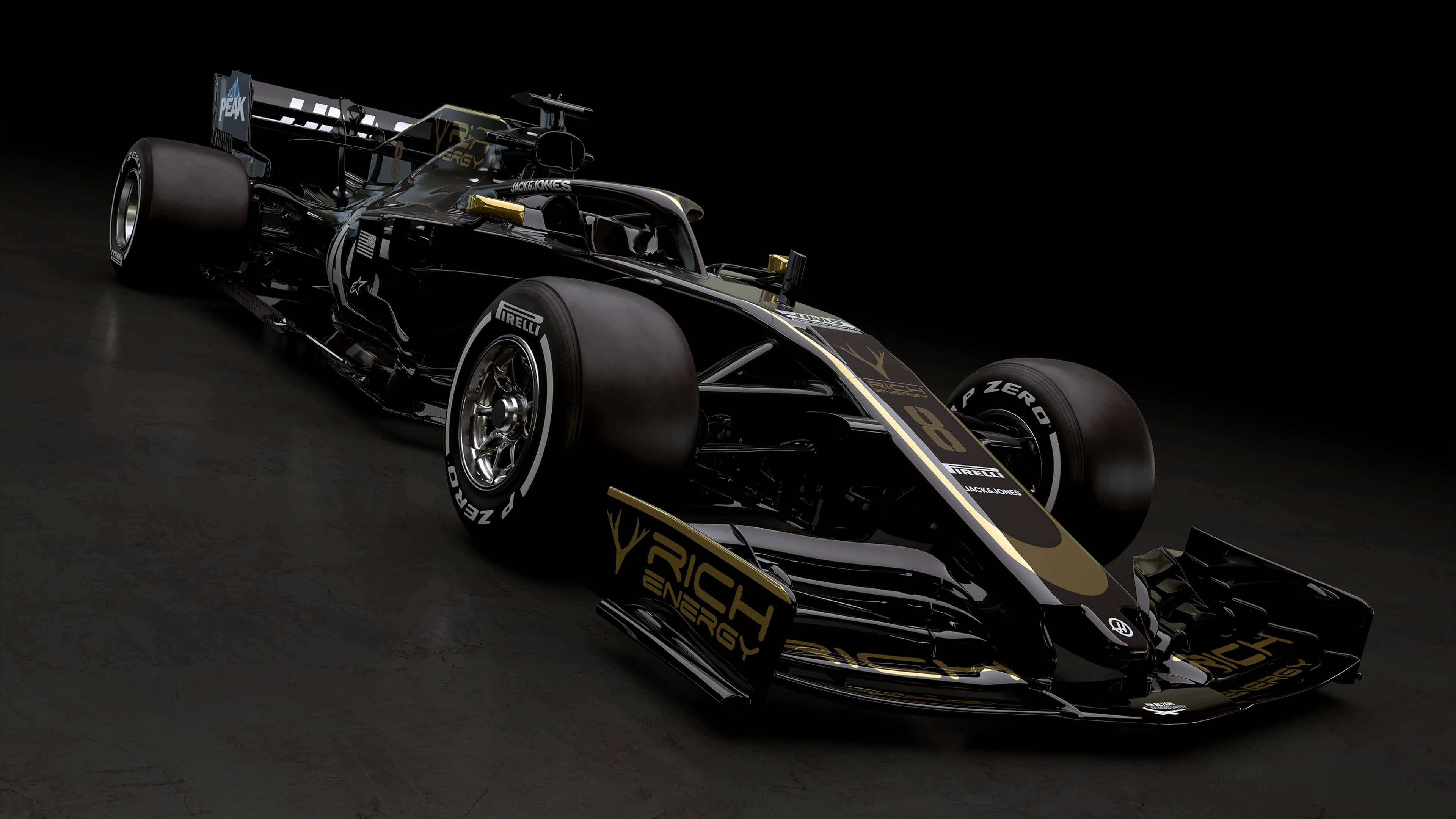 黑色 桌布 壁紙 — 一輛帶有「V RICH ENERGY」品牌標誌的時尚黑色和金色一級方程式賽車，在昏暗的攝影棚中以戲劇性的燈光展示。