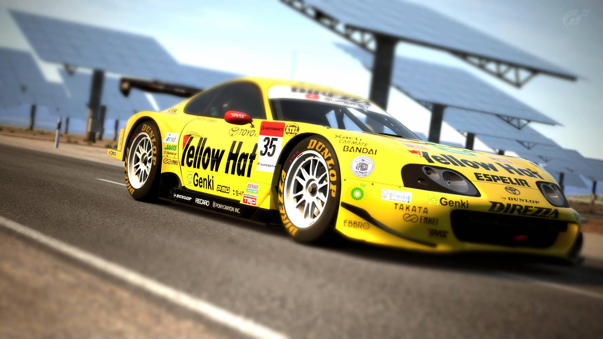 4K 桌布 壁紙 — 一輛帶有「Yellow Hat」品牌的鮮黃色賽車在太陽能板下的賽道上疾馳。