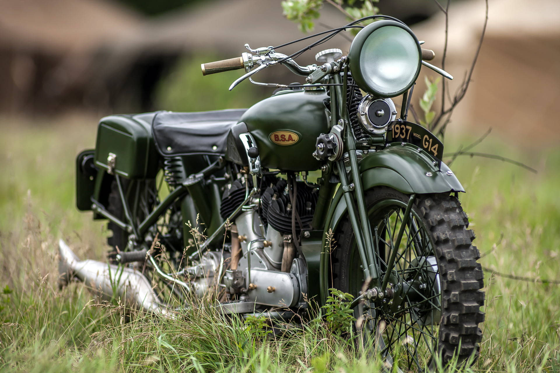 Bobber 桌布 壁紙 — 一輛帶有1937年車牌的復古橄欖綠色BSA摩托車停放在高草叢中，旁邊是一座質樸的木結構建築。