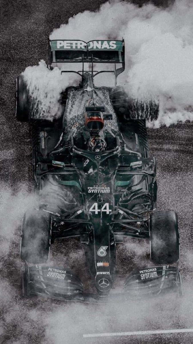 Pixel 3 Grid Autosport 桌布 壁紙 — 一輛帶有44號和Petronas標誌的一級方程式賽車在潮濕的賽道上飛馳，戲劇性地冒煙。