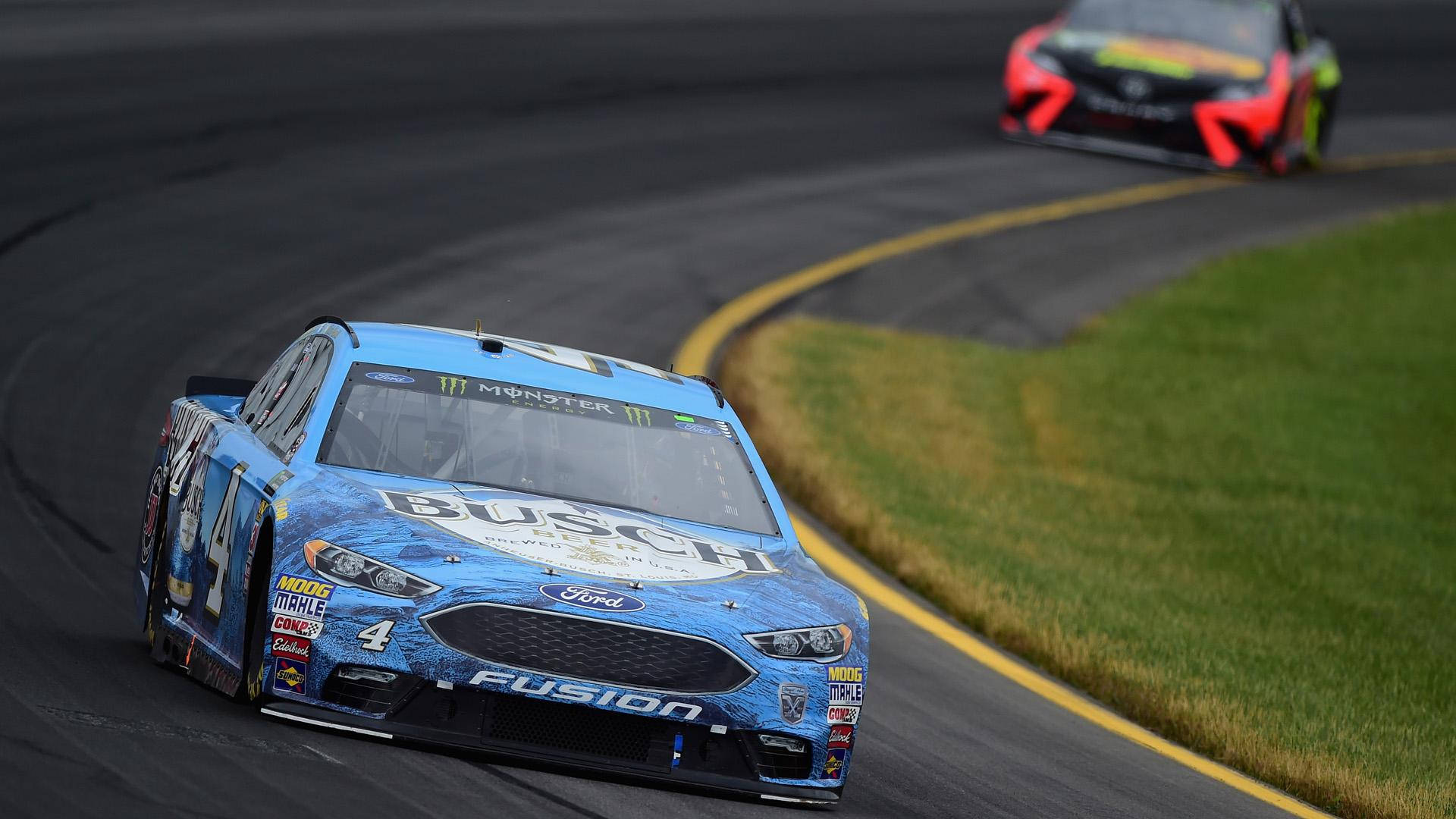 Kevin Harvick 桌布 壁紙 — 一輛帶有Busch品牌標誌的藍色NASCAR福特Fusion在潮濕的瀝青賽道上緊密競賽，一輛紅色賽車緊隨其後。