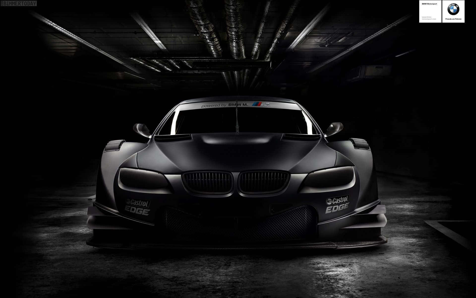 Black Car 4K 桌布 壁紙 — 一輛帶有Castrol EDGE品牌標誌的消光黑色BMW賽車，在黑暗的工業車庫中從上方戲劇性地照亮。