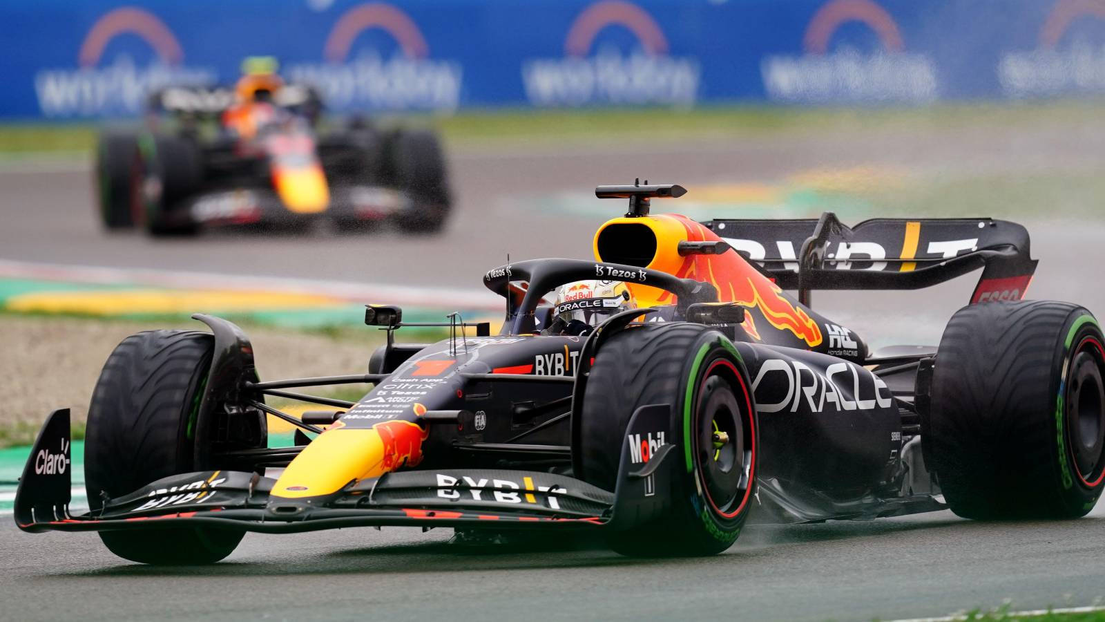 F1 桌布 壁紙 — 一輛帶有Oracle品牌標誌的紅牛車隊一級方程式賽車在濕滑賽道上疾馳，另一輛賽車緊隨其後。