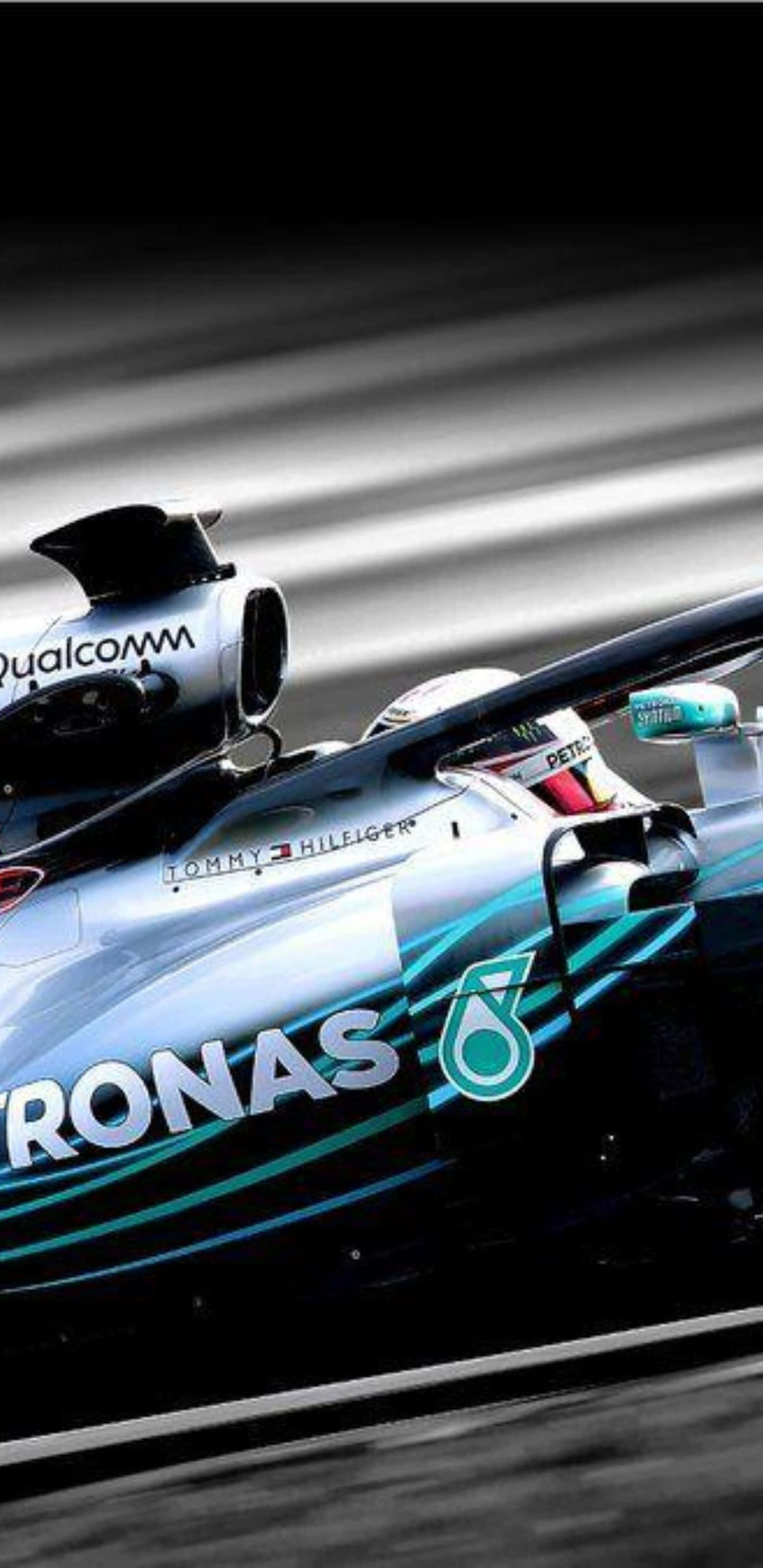 Formula 1 桌布 壁紙 — 一輛帶有Petronas品牌標誌的高速一級方程式賽車在賽道上奔馳，帶有動態模糊條紋。