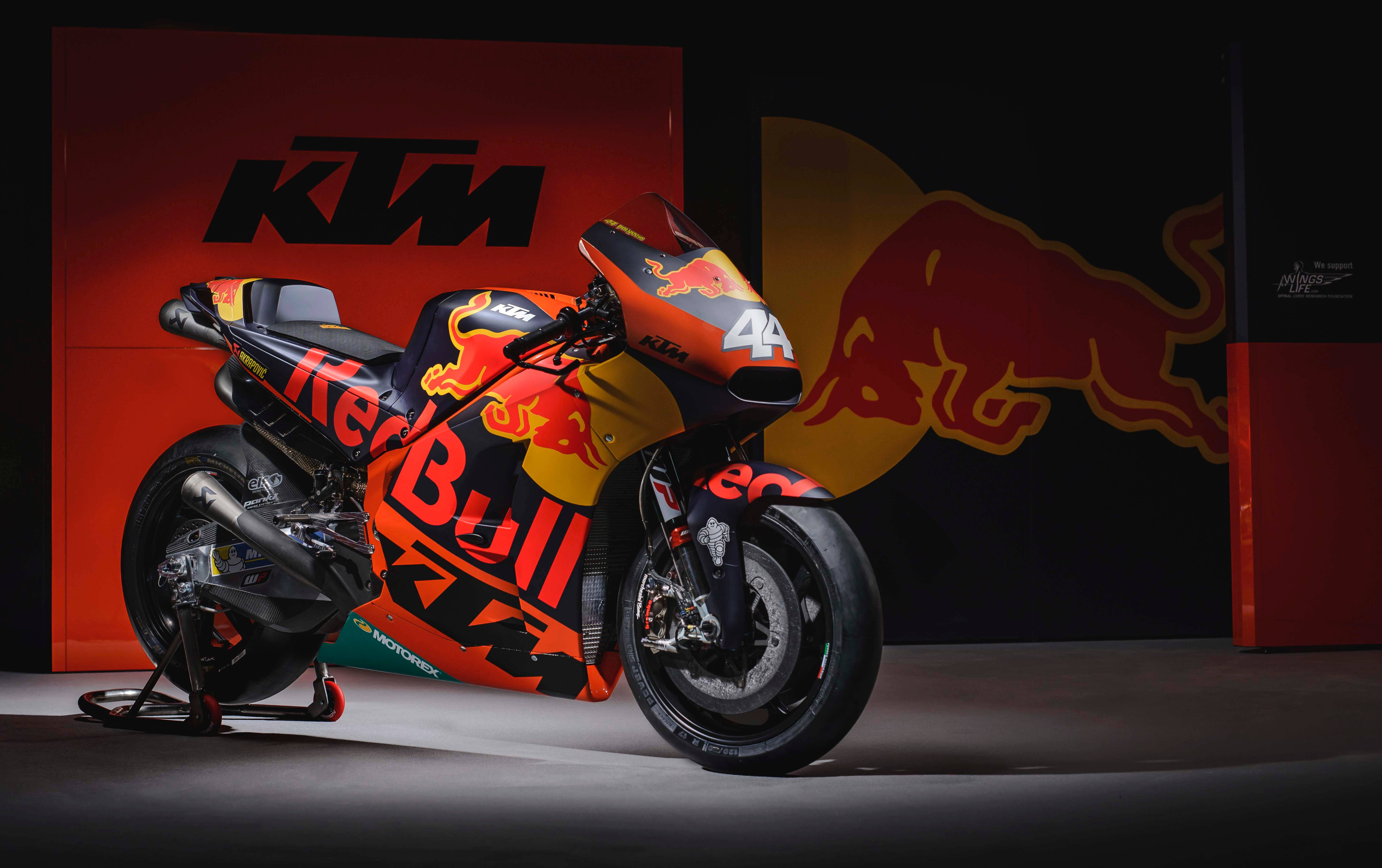 KTM 摩托車 桌布 壁紙 — 一輛帶有Red Bull品牌標誌的時尚KTM MotoGP賽車，在帶有KTM和Red Bull標誌的黑暗背景下戲劇性地照亮。
