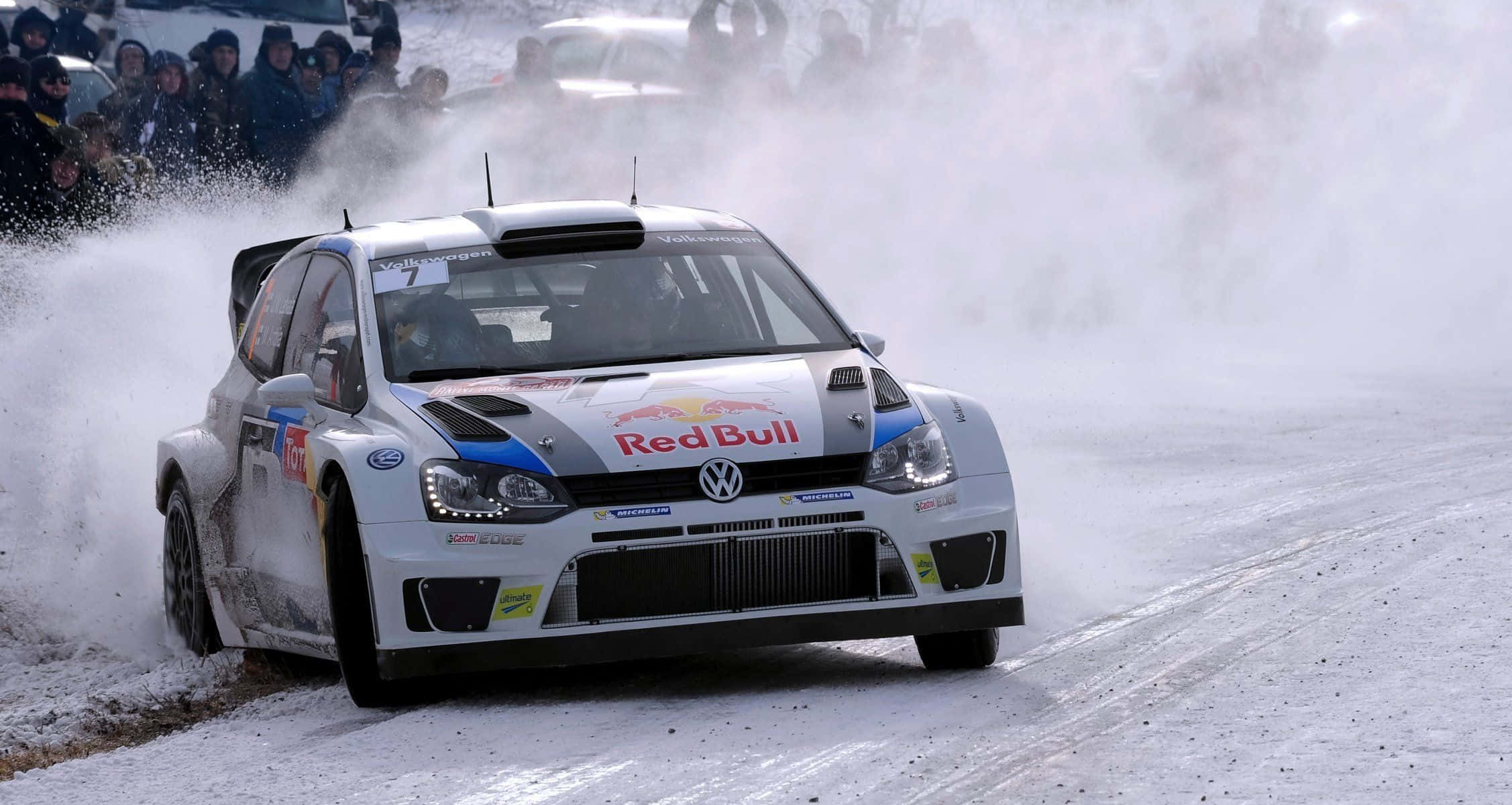 Ice Racing 桌布 壁紙 — 一輛帶有Red Bull品牌標誌的白色福斯偉根拉力賽車在雪地彎道疾馳，激起大量雪和冰花。