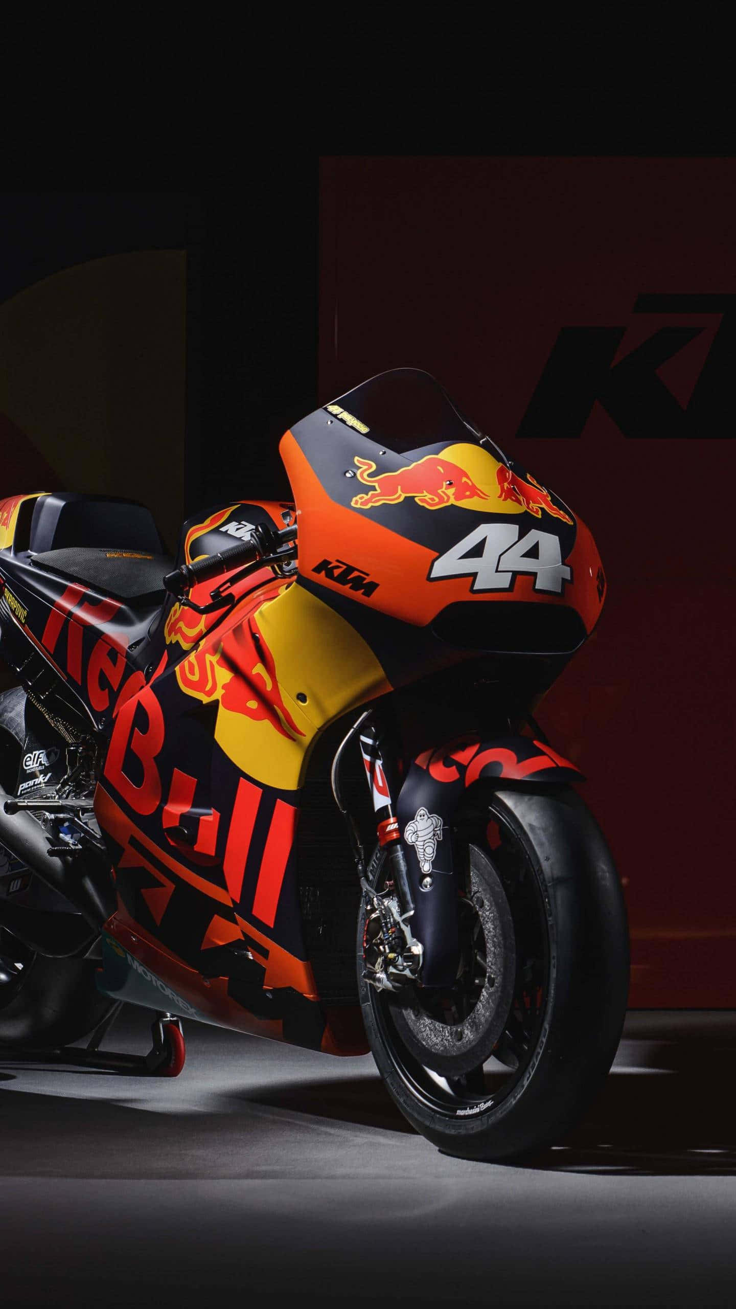 Motorcycle iPhone 桌布 壁紙 — 一輛帶有Red Bull塗裝和44號的時尚KTM MotoGP機車，在戲劇性的工作室燈光下閃耀。
