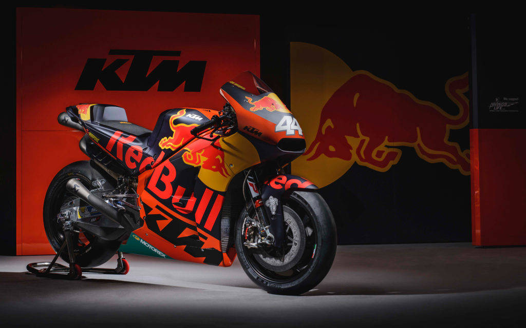 Ktm Bike 桌布 壁紙 — 一輛帶有Red Bull塗裝的KTM MotoGP賽車，在工作室環境中放在支架上，背景是品牌牆壁。