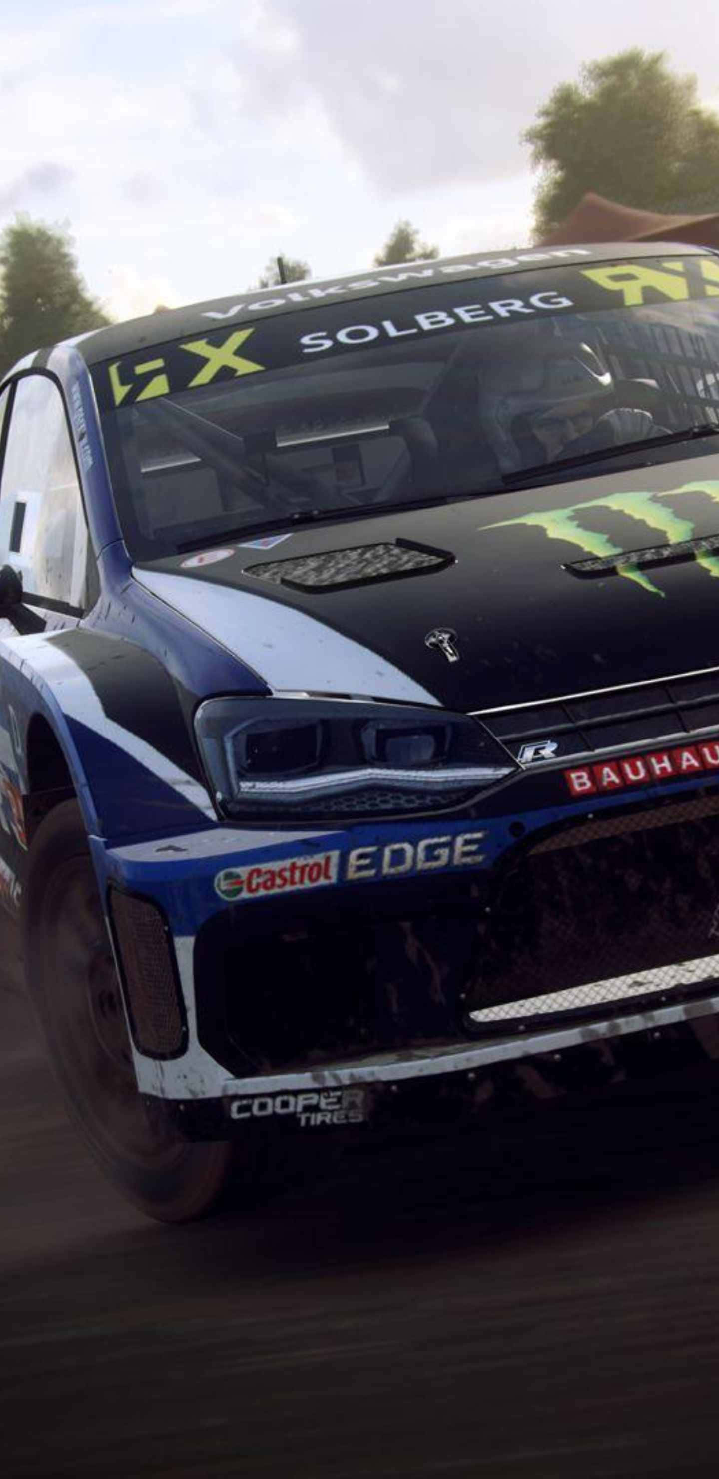 Android Dirt Rally 桌布 壁紙 — 一輛帶有Solberg和Monster Energy標誌的藍黑色Volkswagen拉力賽車在森林泥路上飛馳。