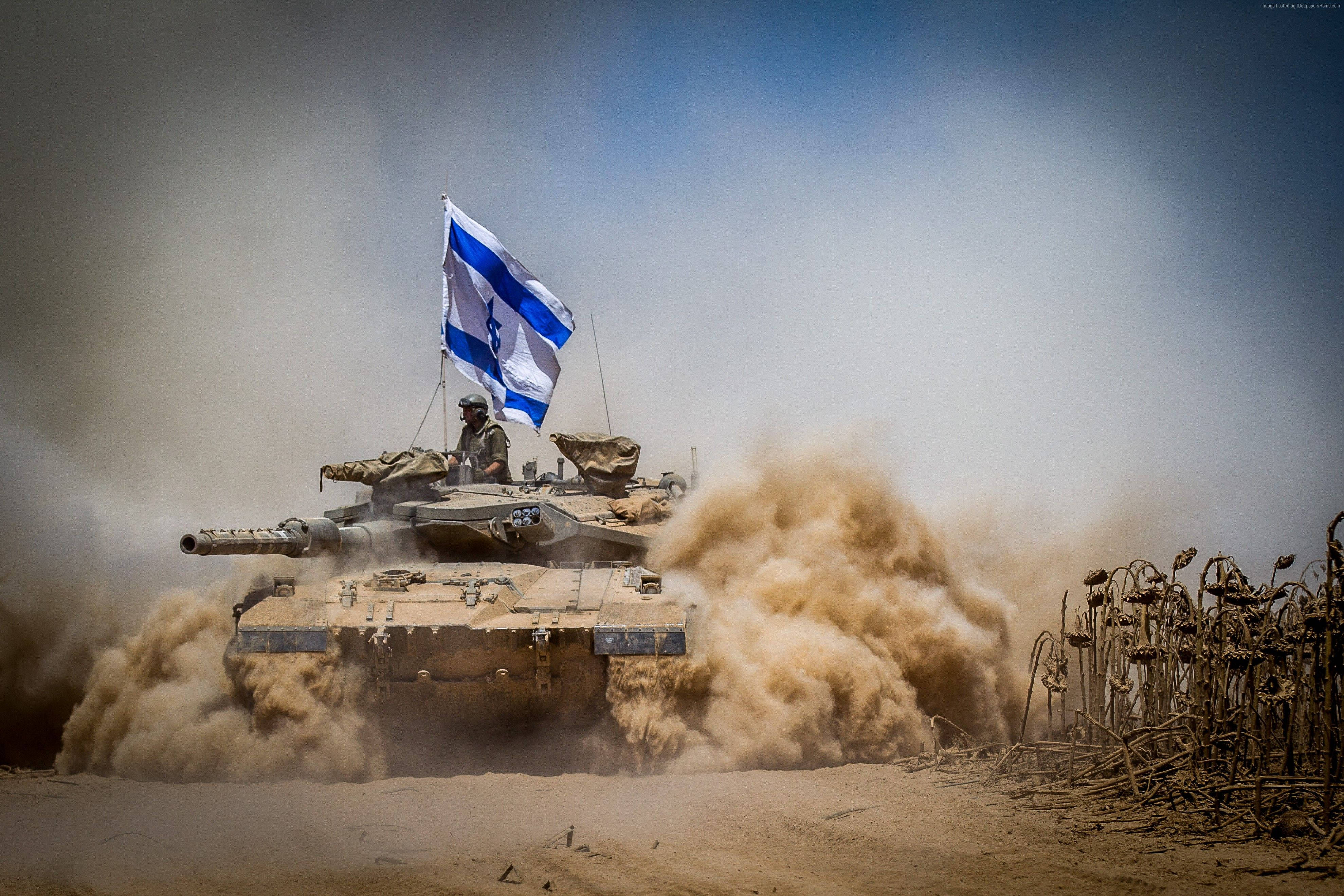 Israel Flag 桌布 壁紙 — 一輛帶有以色列國旗的軍用坦克在晴朗的藍天下穿越沙漠地形，揚起巨大的塵雲。
